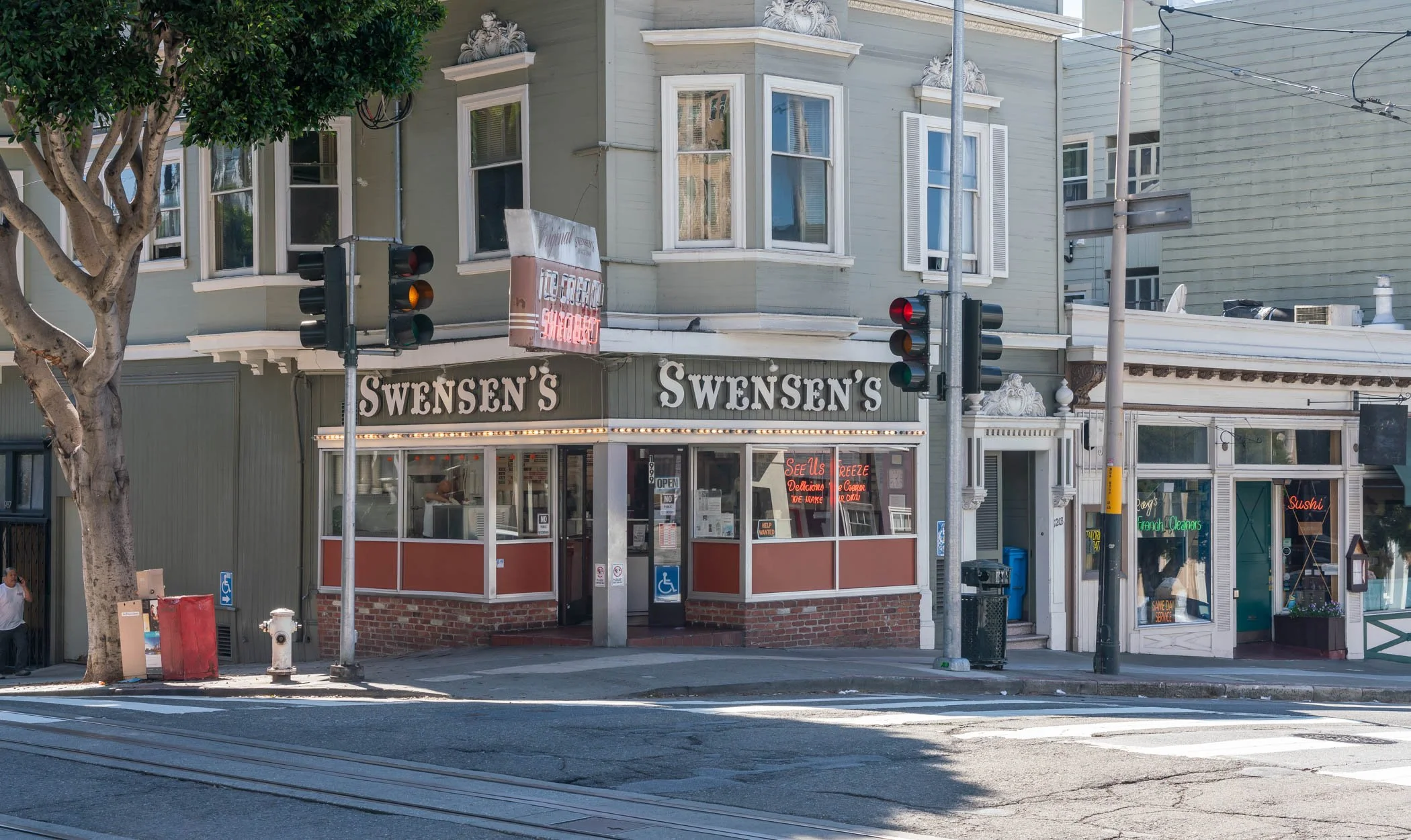 Street view of Swensen's ice cream shop with a vintage building facade, traffic lights, and a tree in front.