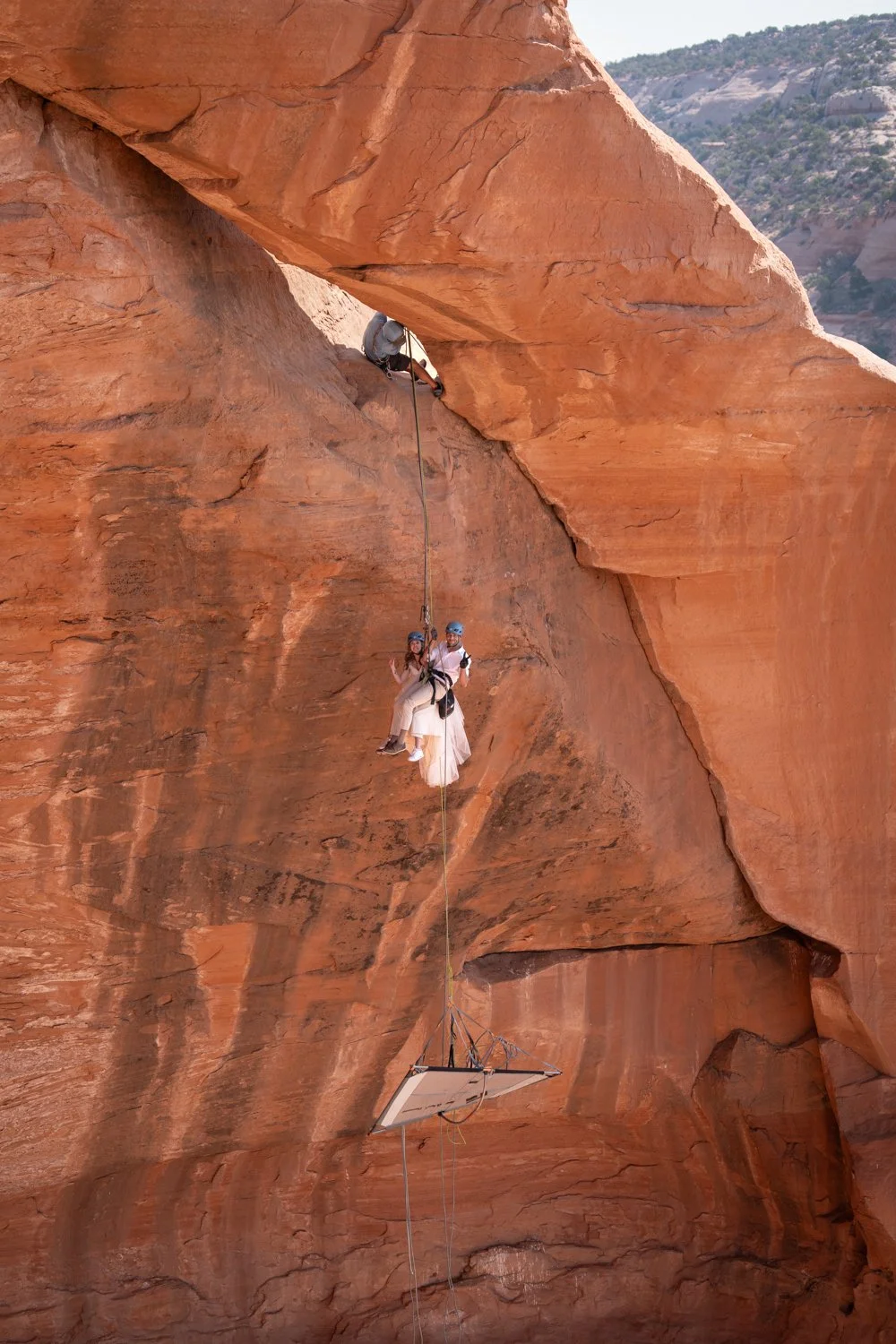 A bride and groom descend to a suspended portaledge after rock climbing in Moab, Utah.