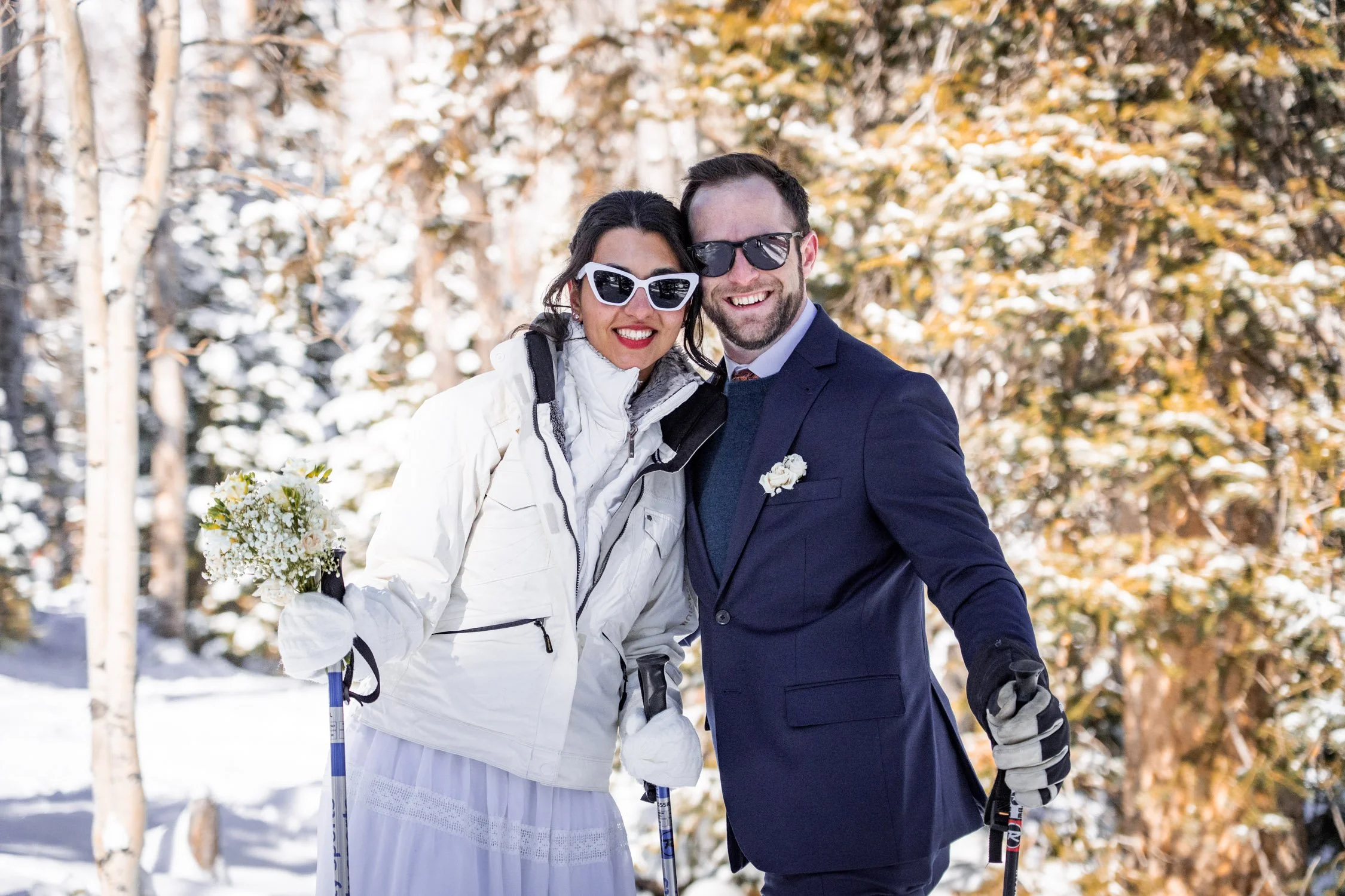 A bride and groom smile at the camera on a ski resort in Colorado.
