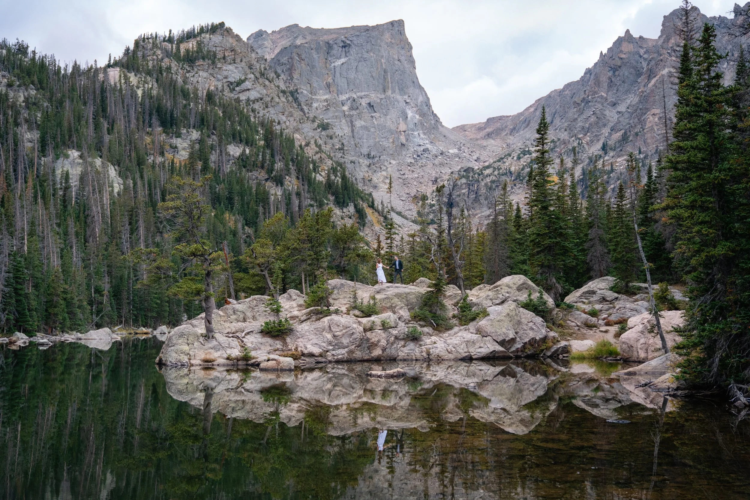 A bride and groom hike along rocks in Rocky Mountain National Park, Colorado.
