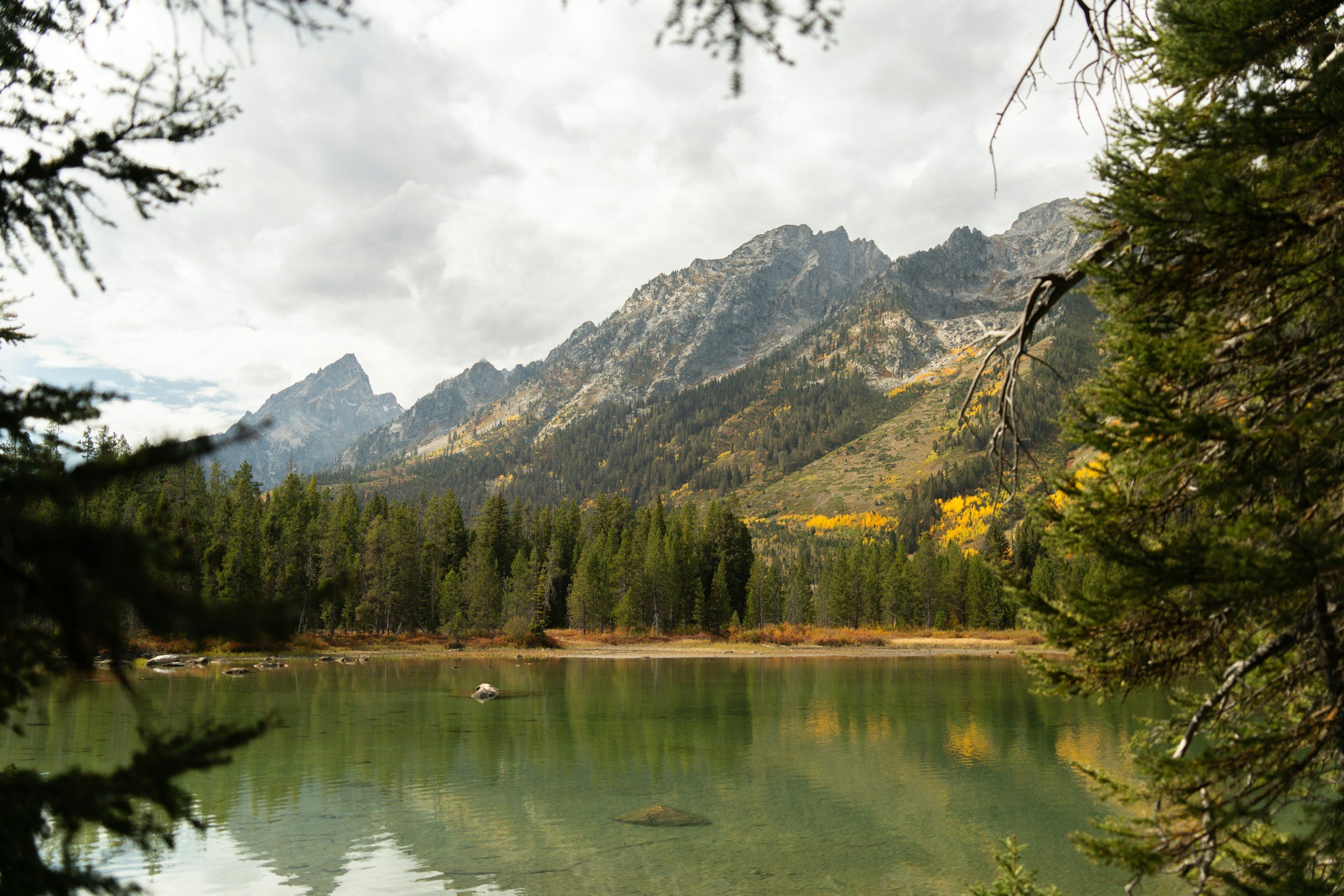 A vast mountain overlooks an alpine lake during fall in Colorado.