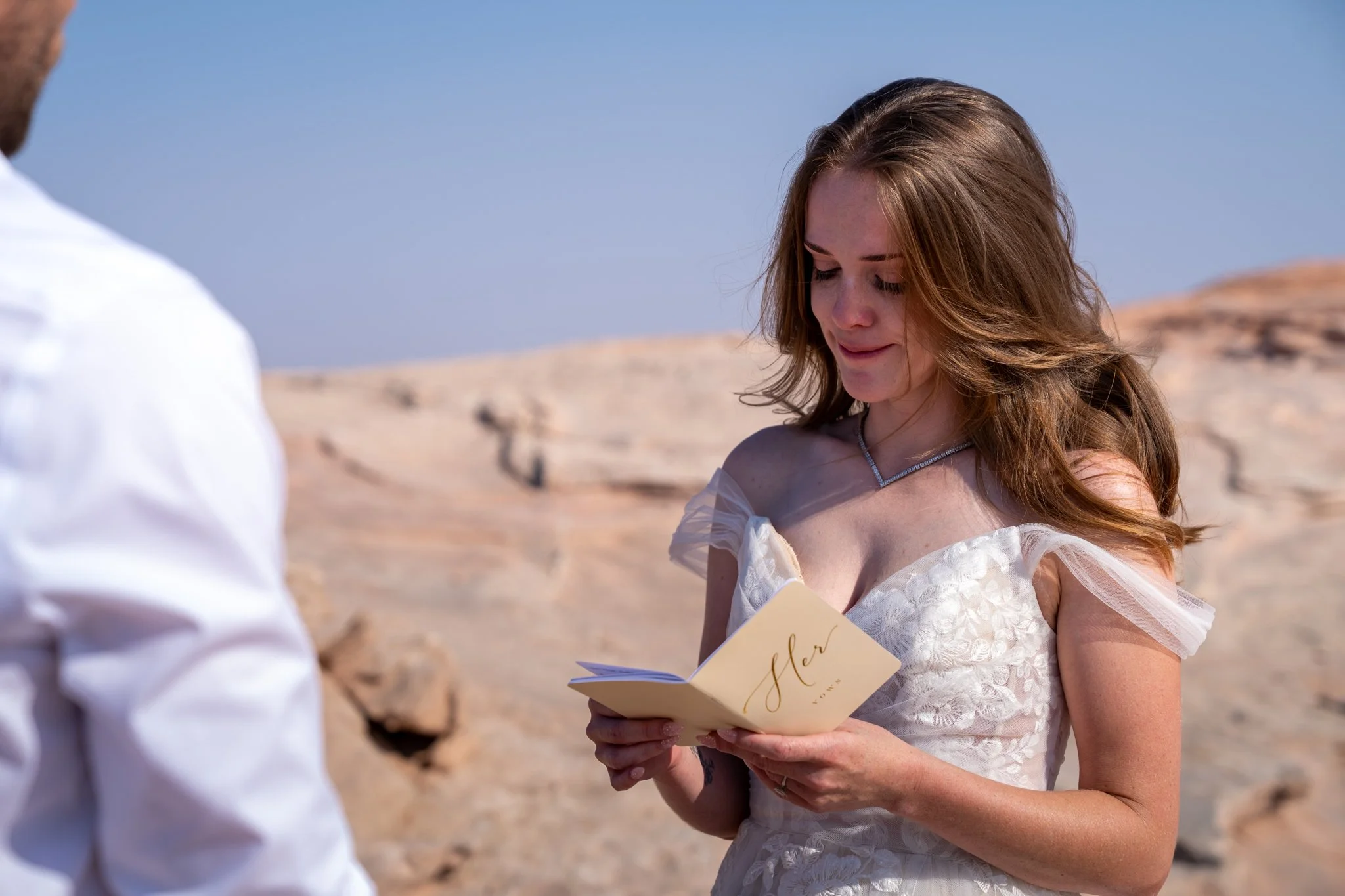 A bride reads vows to her husband on top of a rock in Moab.