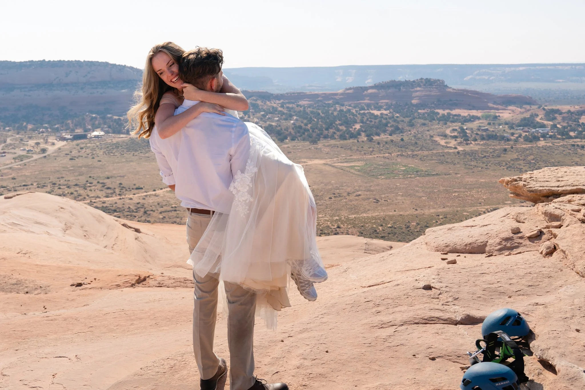 A groom picks up his laughing bride on top of a rock in Moab.