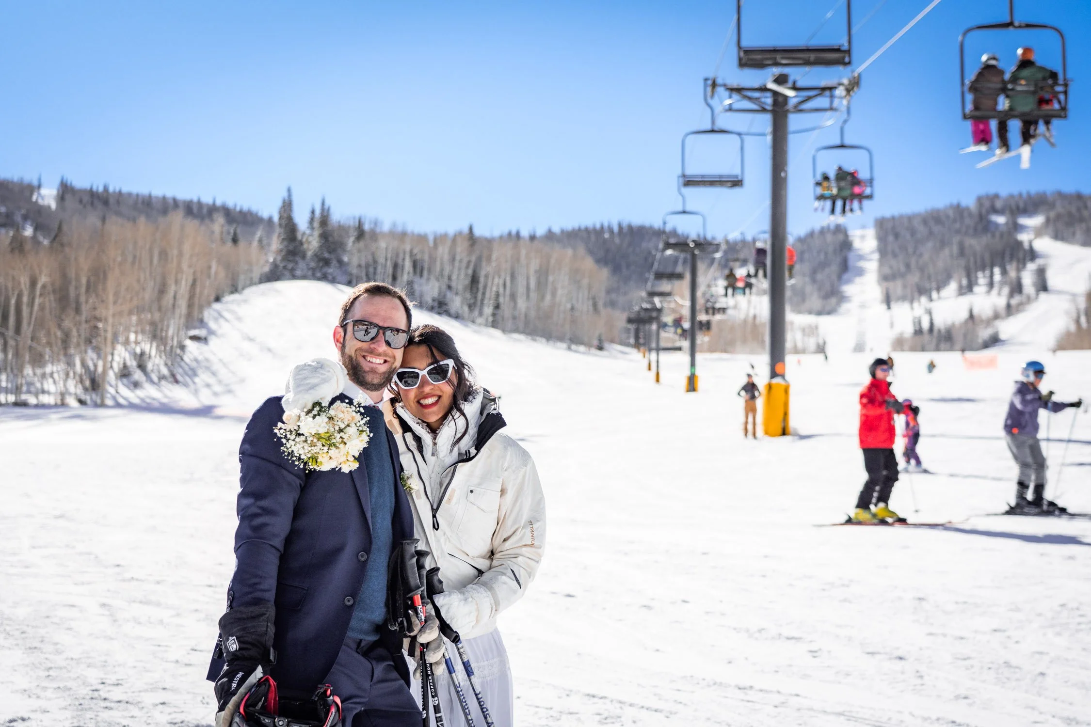 A bride and groom hug under a ski lift on their elopement day.