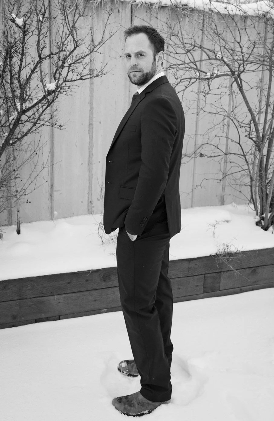 A groom looks at the camera in winter.