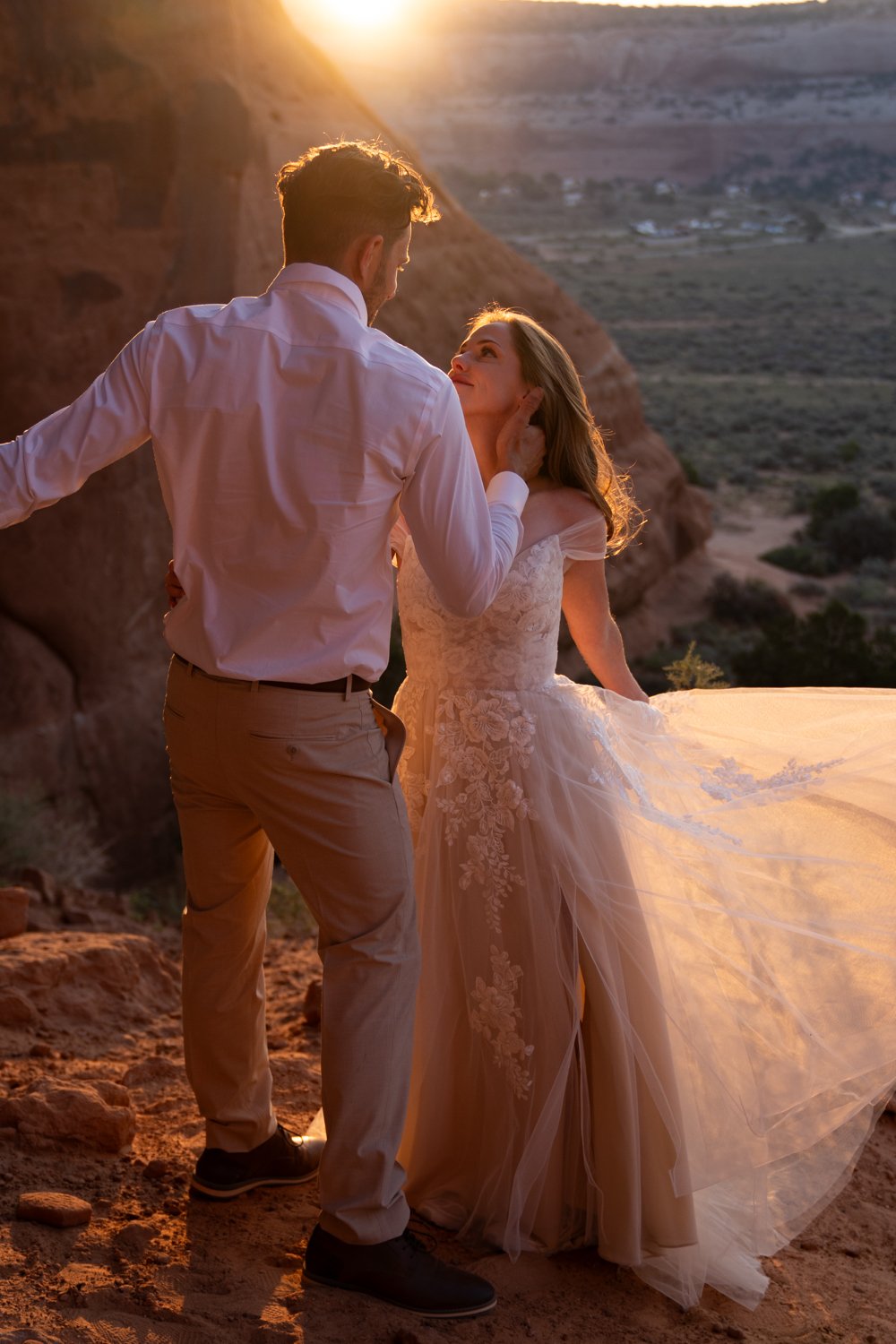 A bride and groom dance in the sunrise light in Moab.