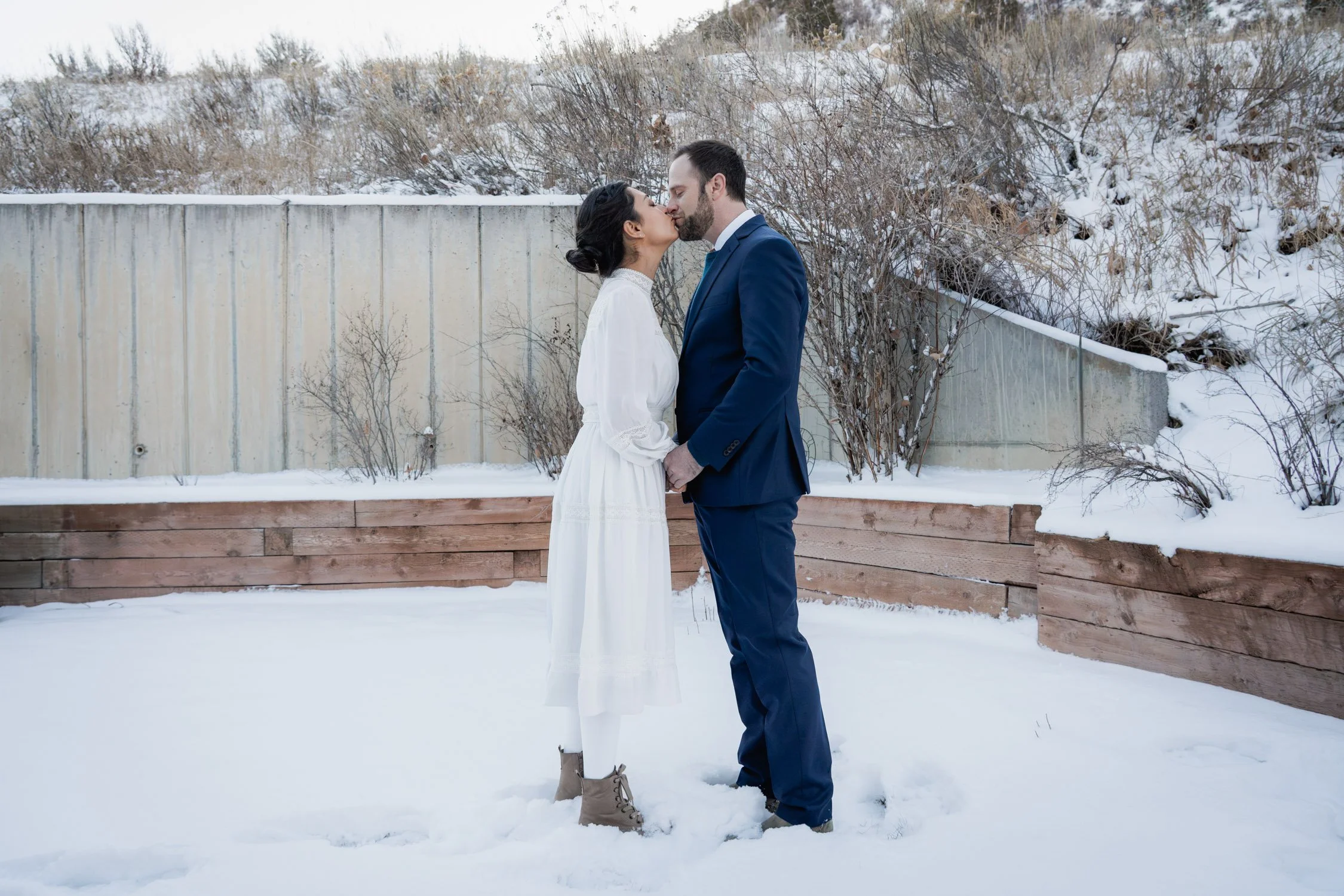 A bride and groom kiss in the early winter morning.