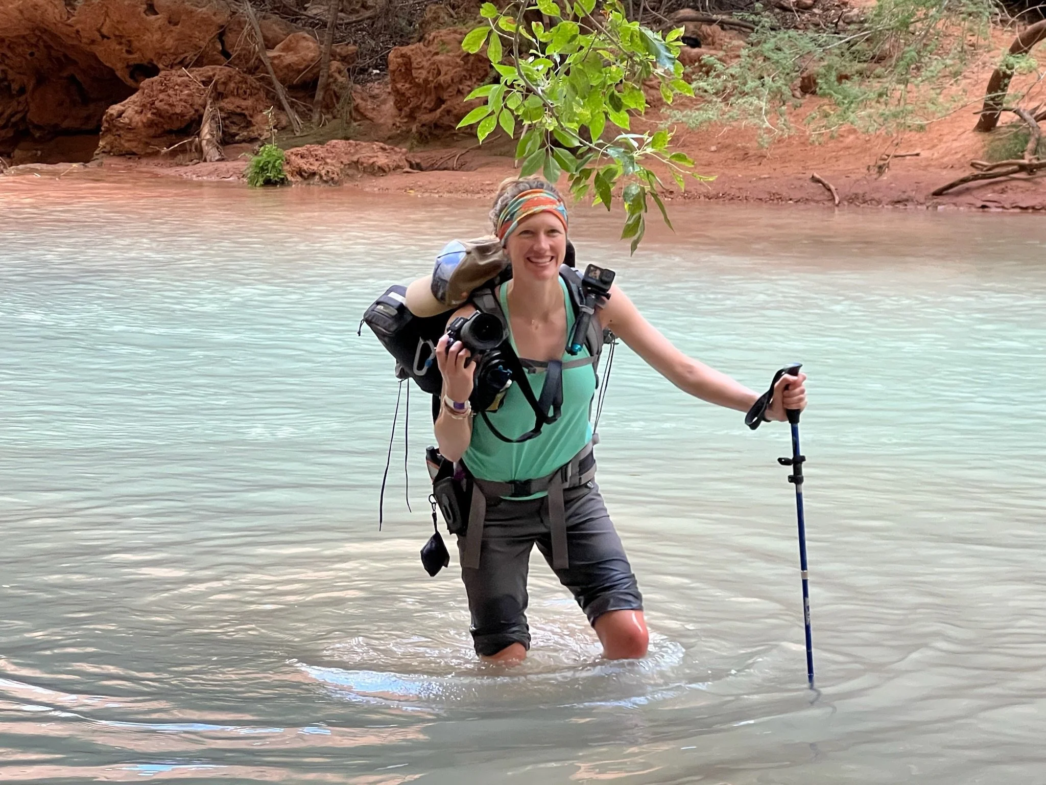 Girl holding camera while crossing river in Arizona.
