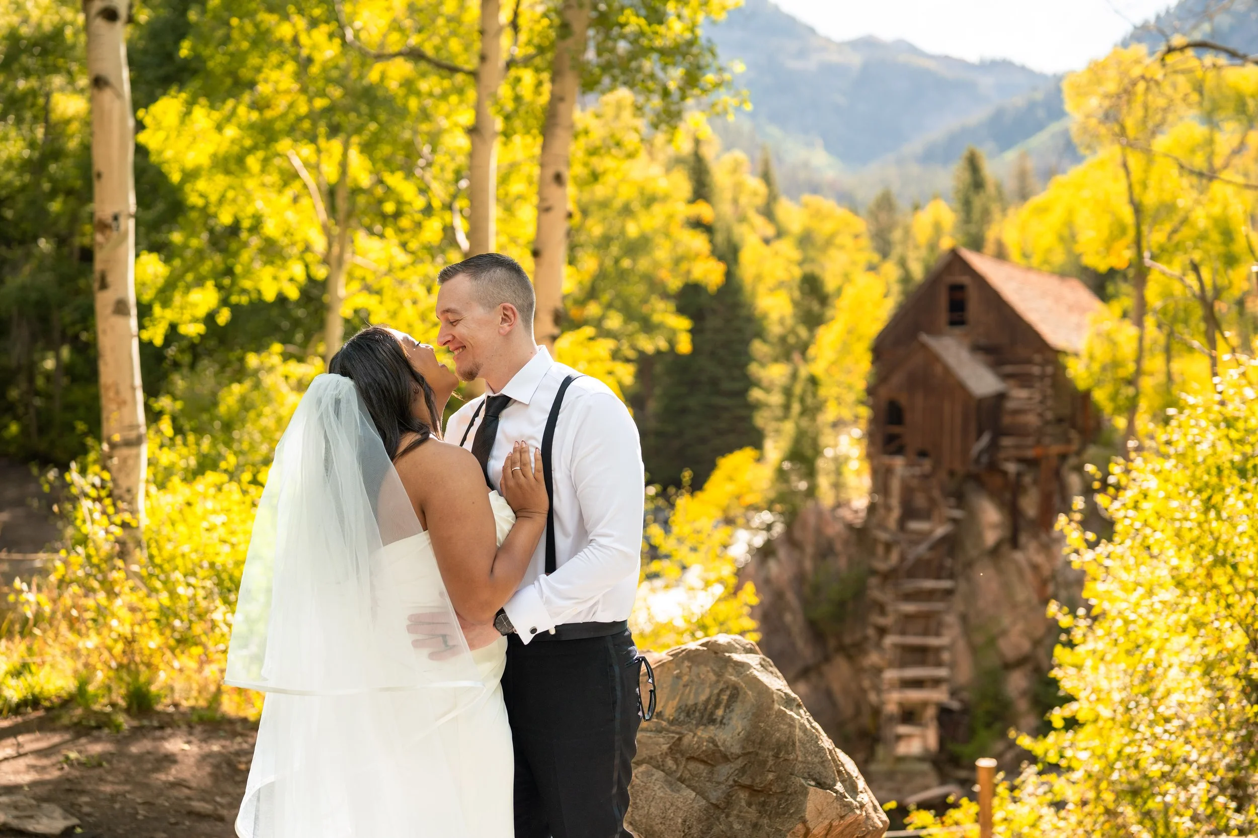 A bride and groom hold each other in front of Crystal Mill in Marble, Colorado during the fall.