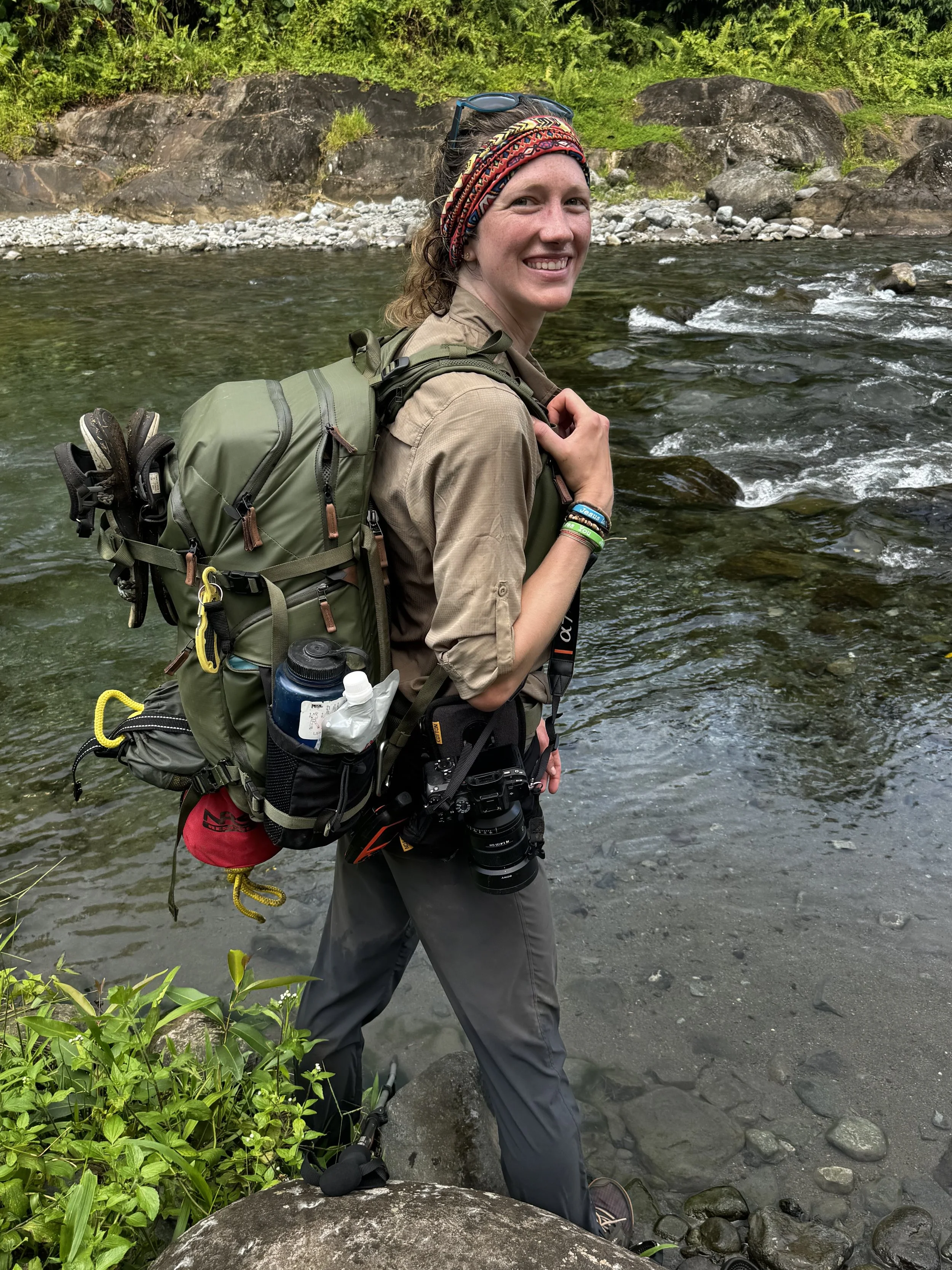 Girl standing in river in Vanuatu, smiling with a camera.