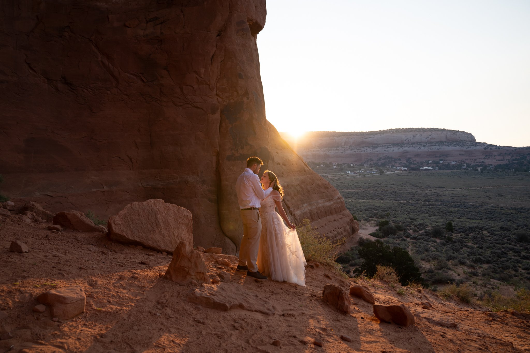 A bride and groom hold each other in the sunrise light in Moab.