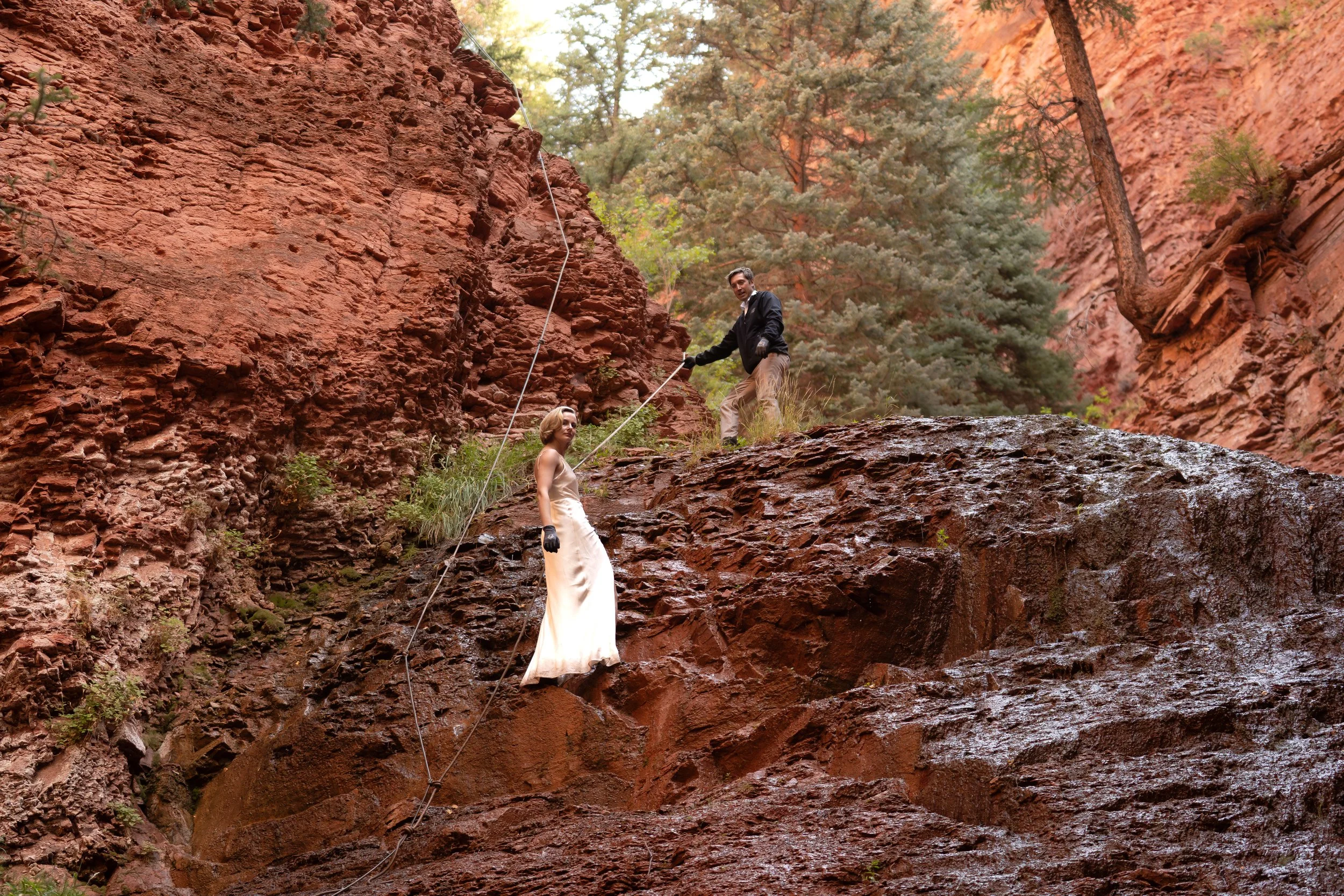 A bride and groom use ropes to climb up the side of a cliff to waterfalls near Aspen, Colorado.