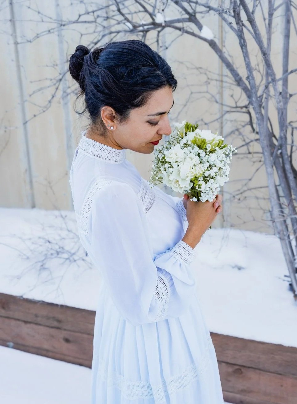 A bride smells her bouquet of flowers in winter.