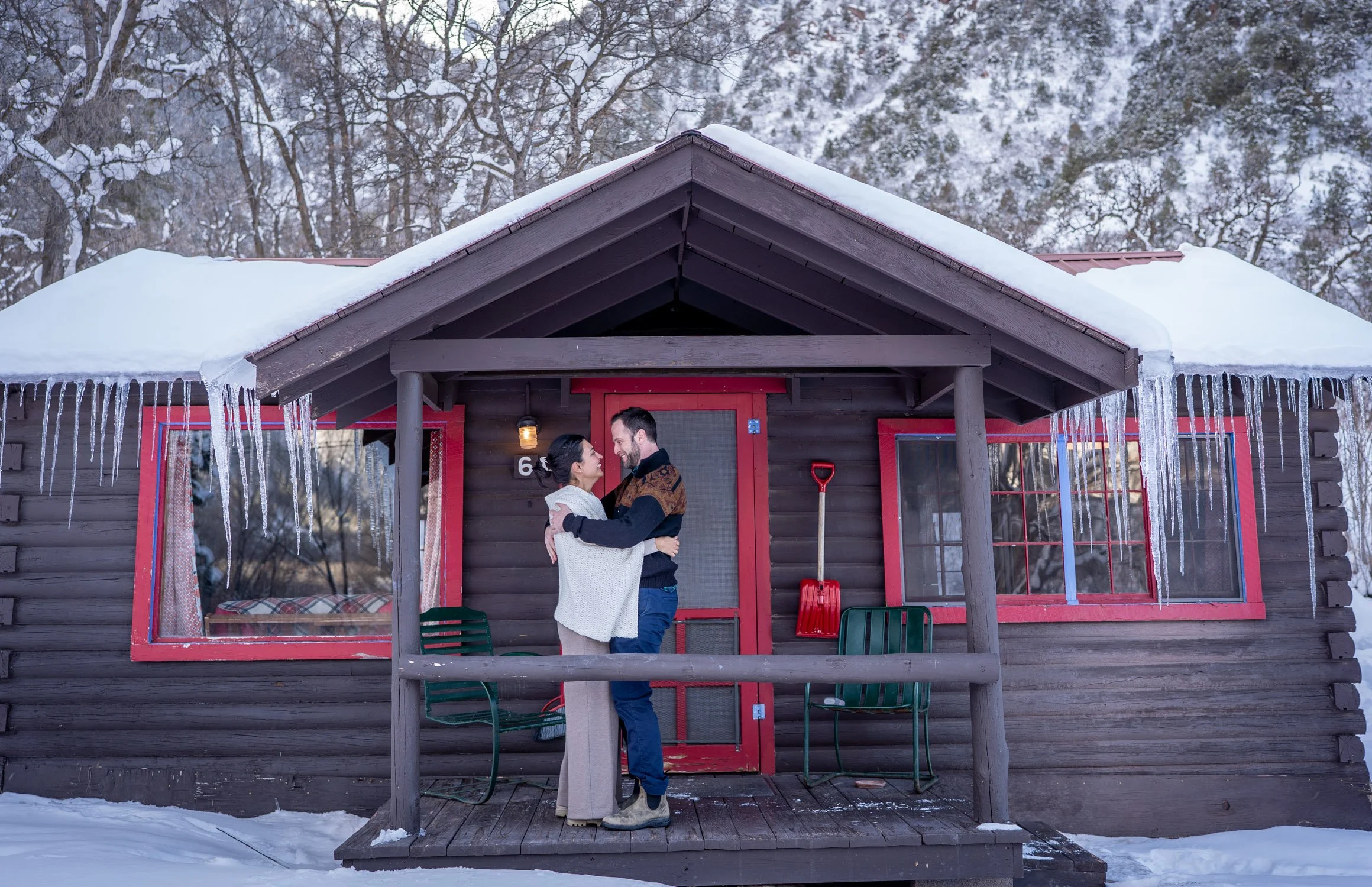 A bride and groom hug outside of a cabin in Colorado.