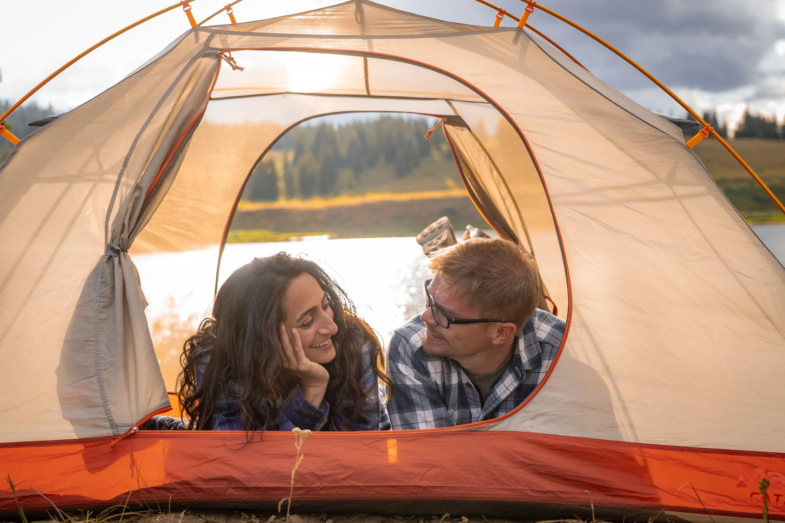 A couple smiles at each other from inside a tent at sunset in Colorado.