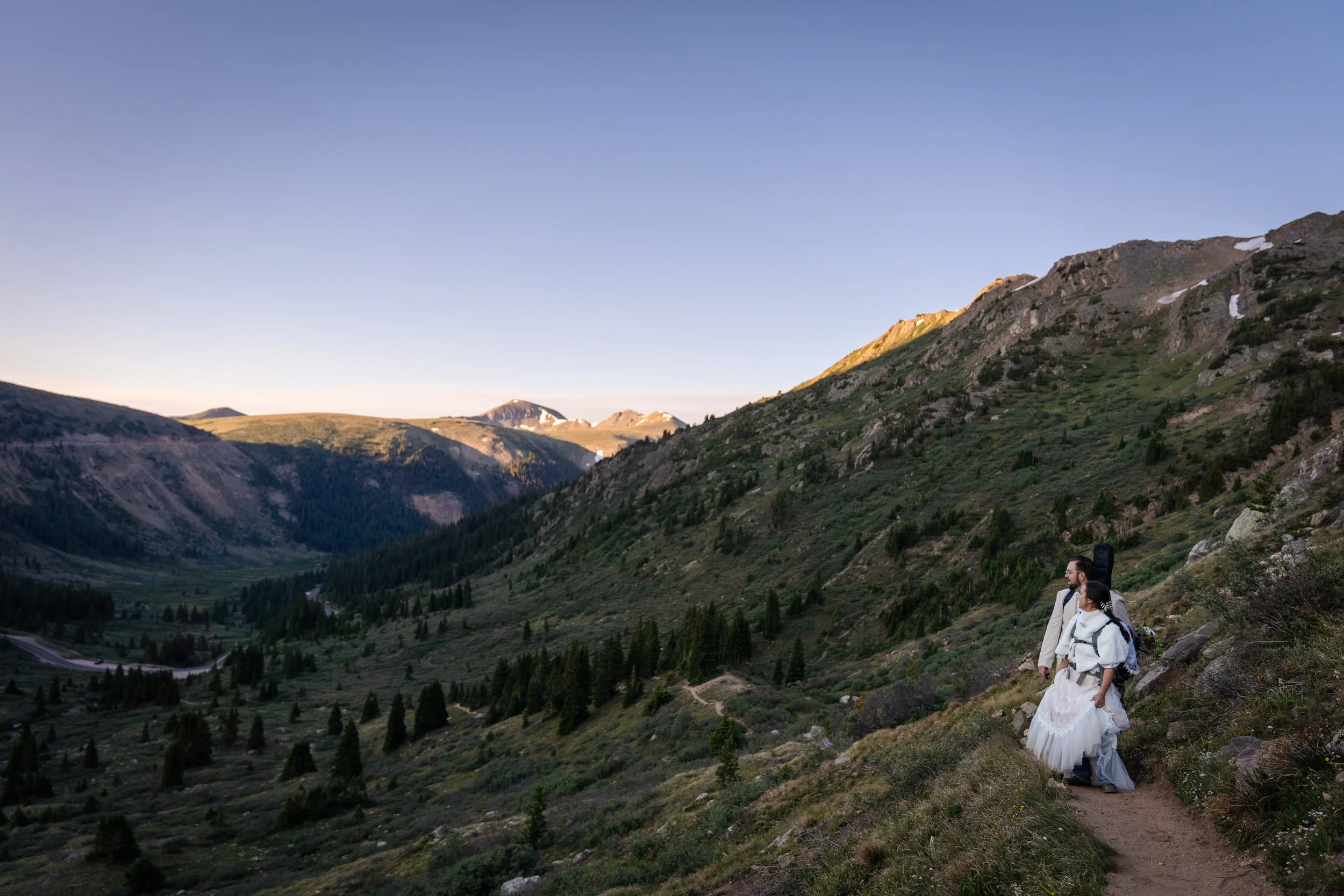 A couple stops mid-hike to admire the mountain view at sunrise in Colorado.