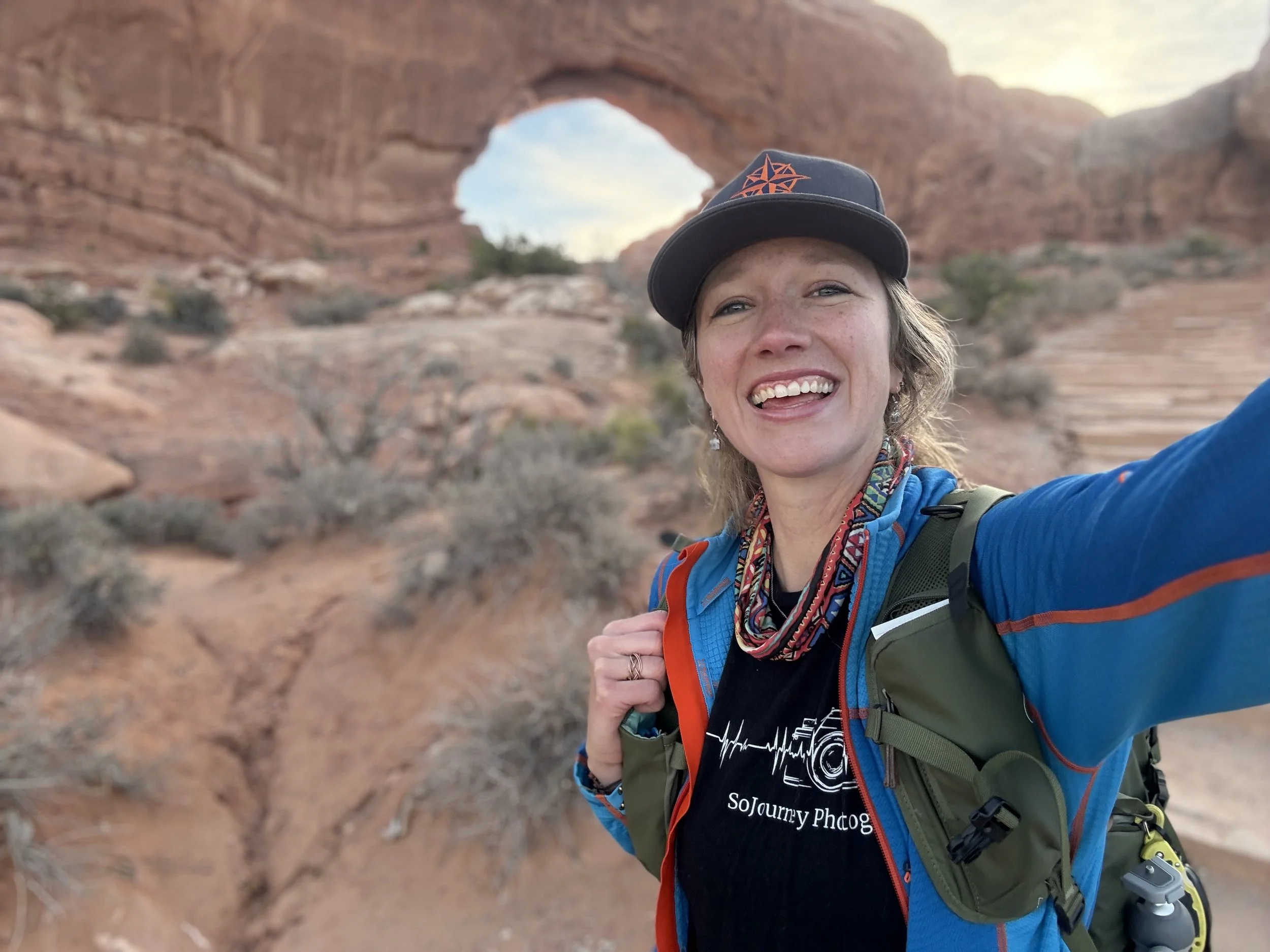 Girl happy and taking selfie in front of arch in Moab, Utah.