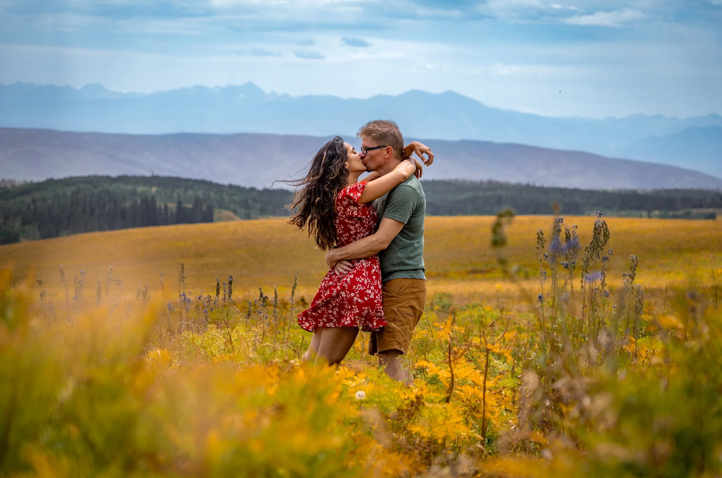 A couple kisses in wildflowers in Colorado.