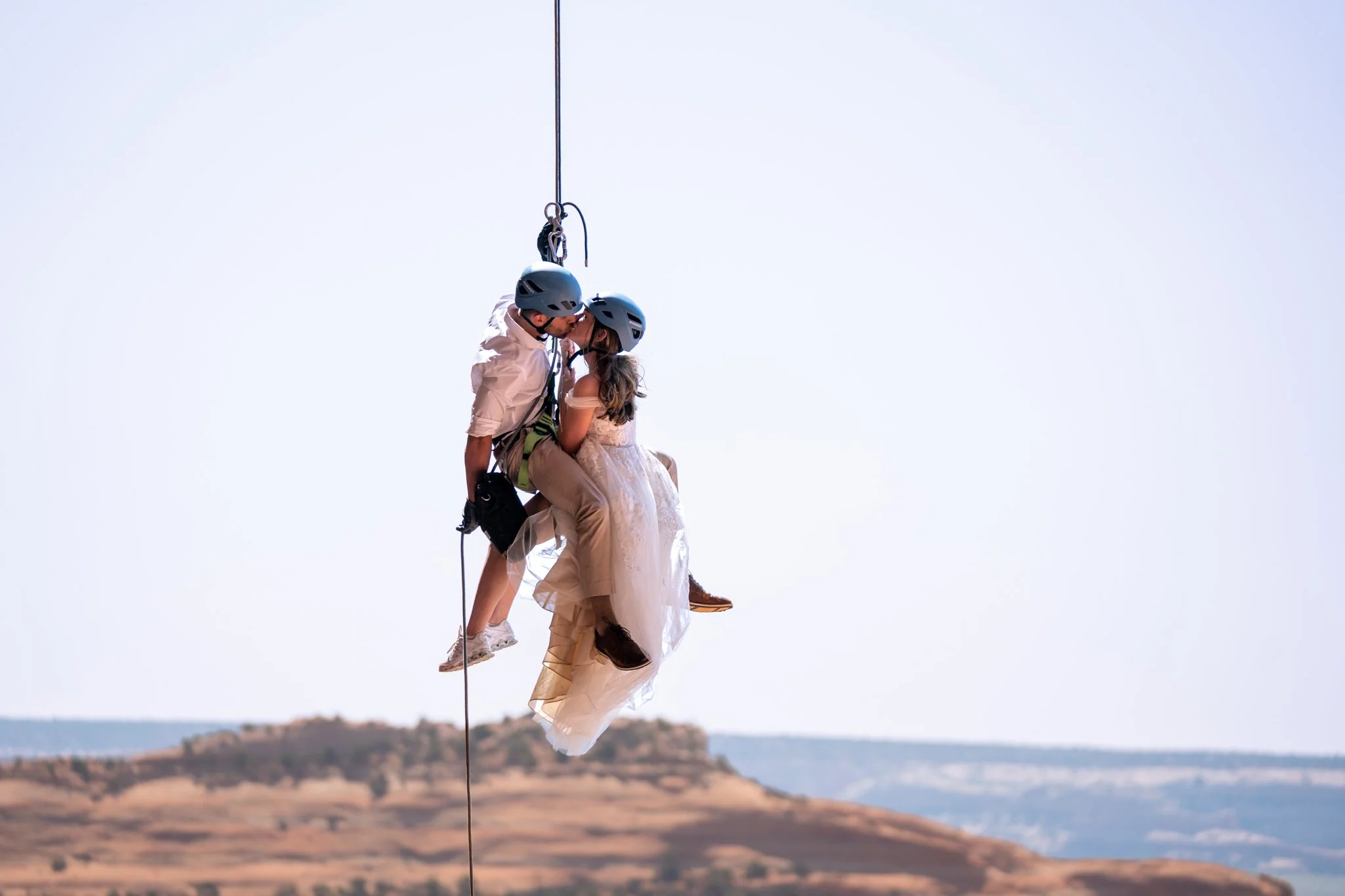 A bride and groom rappel from a rock in Moab, Utah.