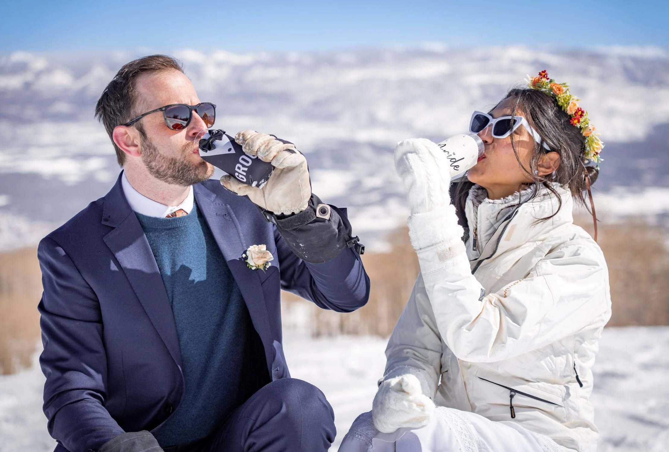 A bride and groom share a drink together on a ski hill in Colorado.