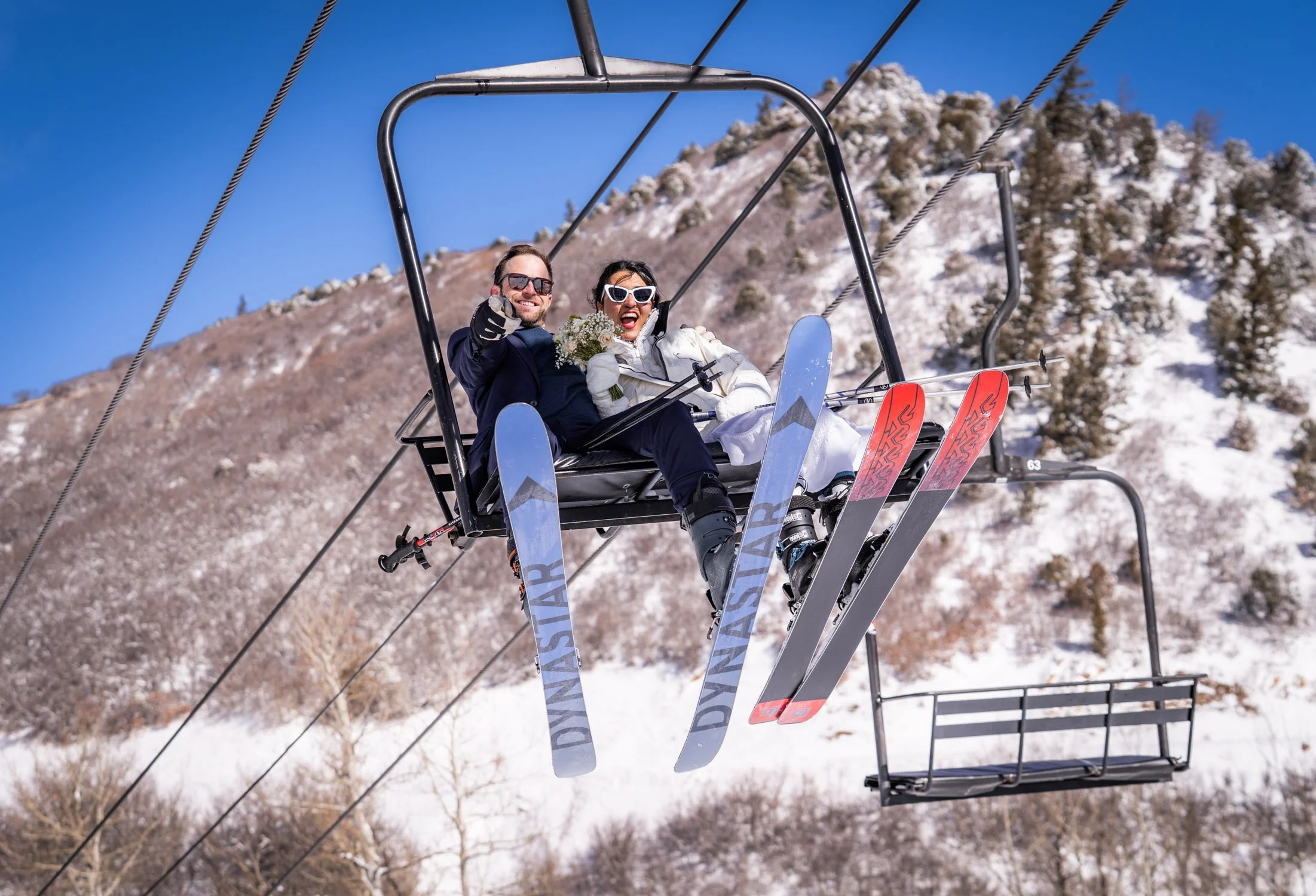 A bride and groom laugh on a ski chair on their elopement day.