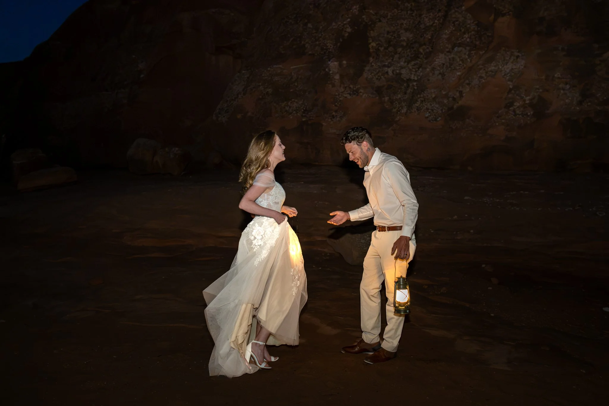 A bride and groom have an emotional look in the desert dark by lantern light.