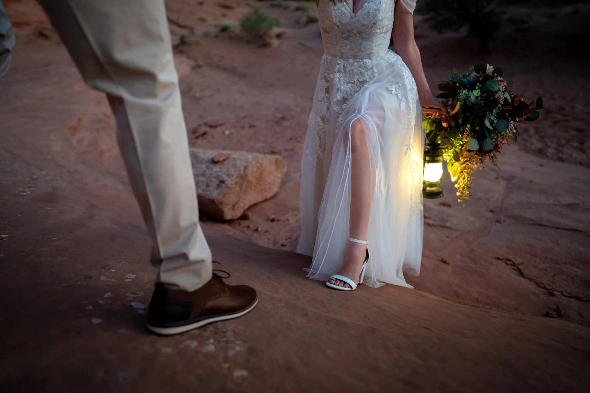 A closeup of the bride and groom's shoes as they walk up a red rock in Moab, Utah.