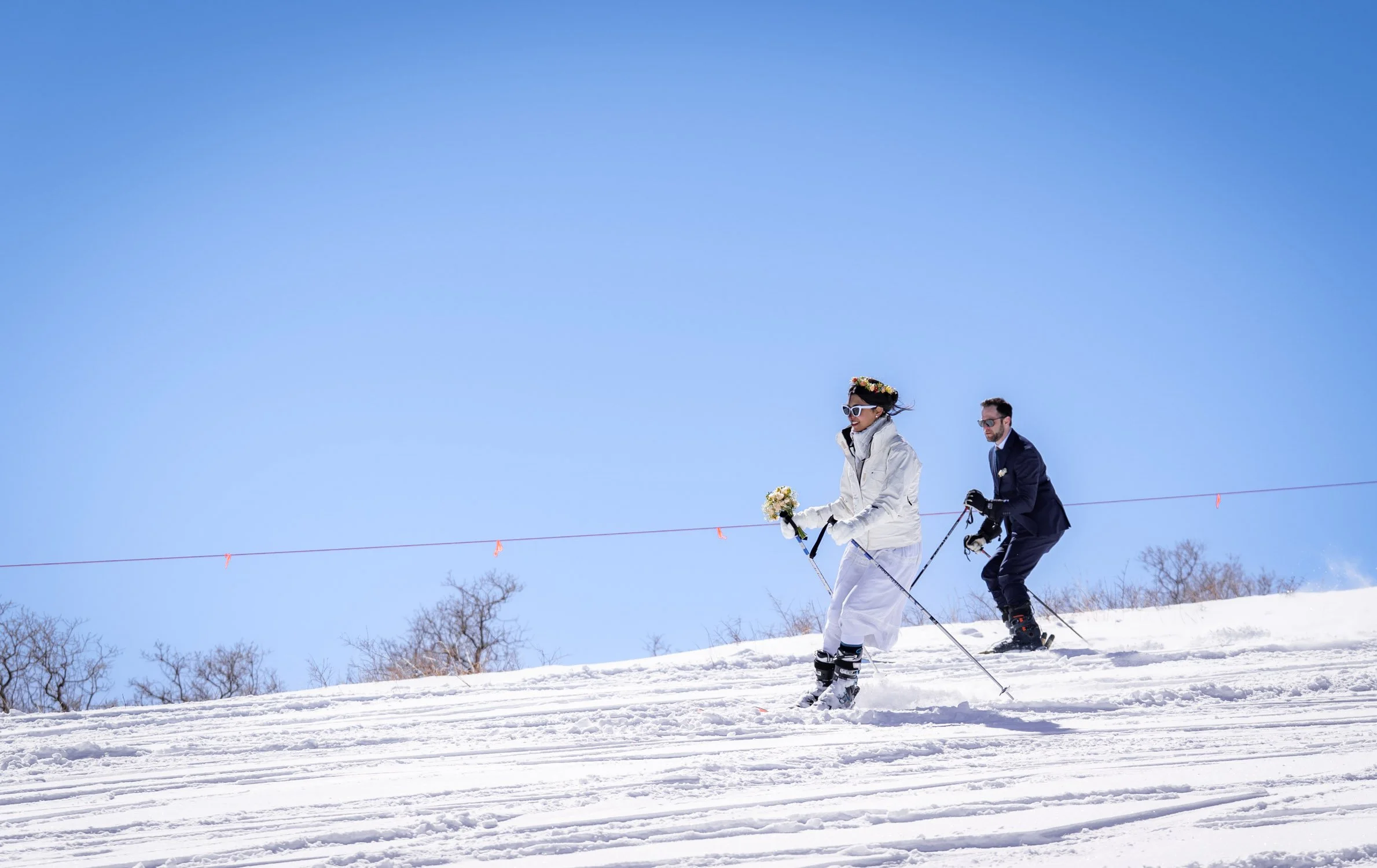 A bride and groom race down a ski mountain together in Colorado.