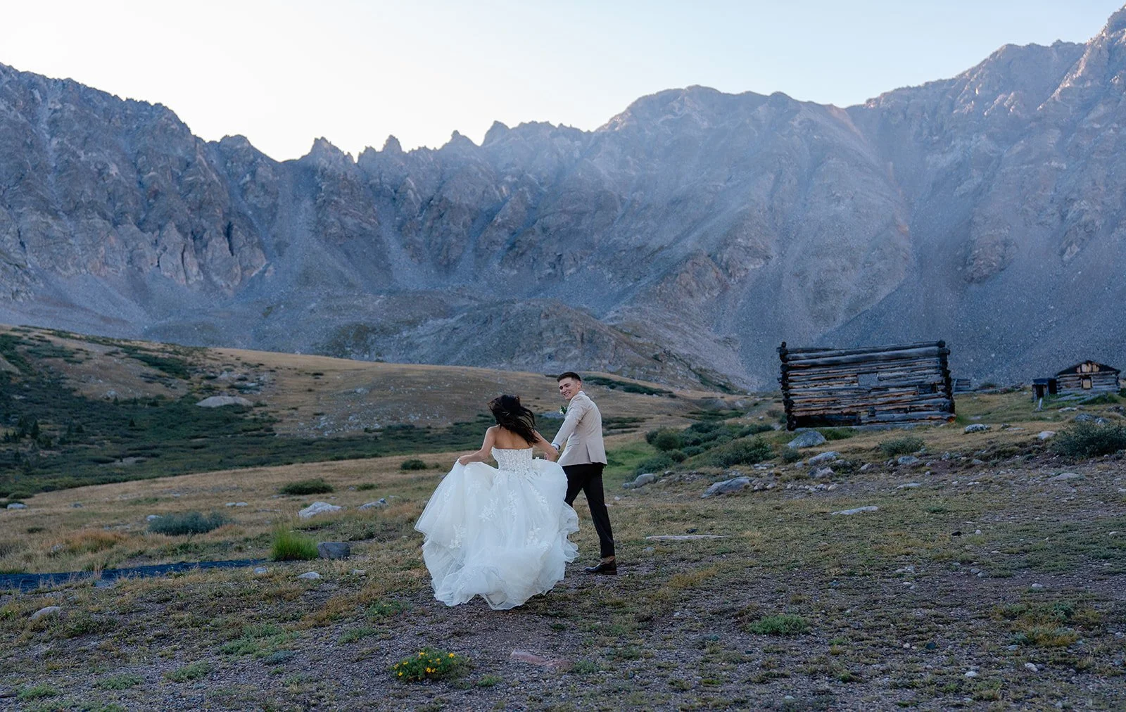 A bride and groom run into the mountains at sunrise in Frisco, Colorado.