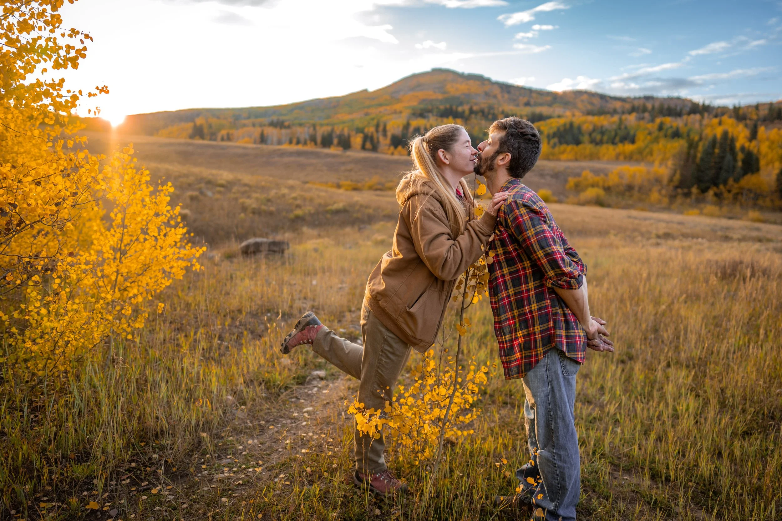 A bride and groom kiss over an aspen tree in the fall colors of Colorado.