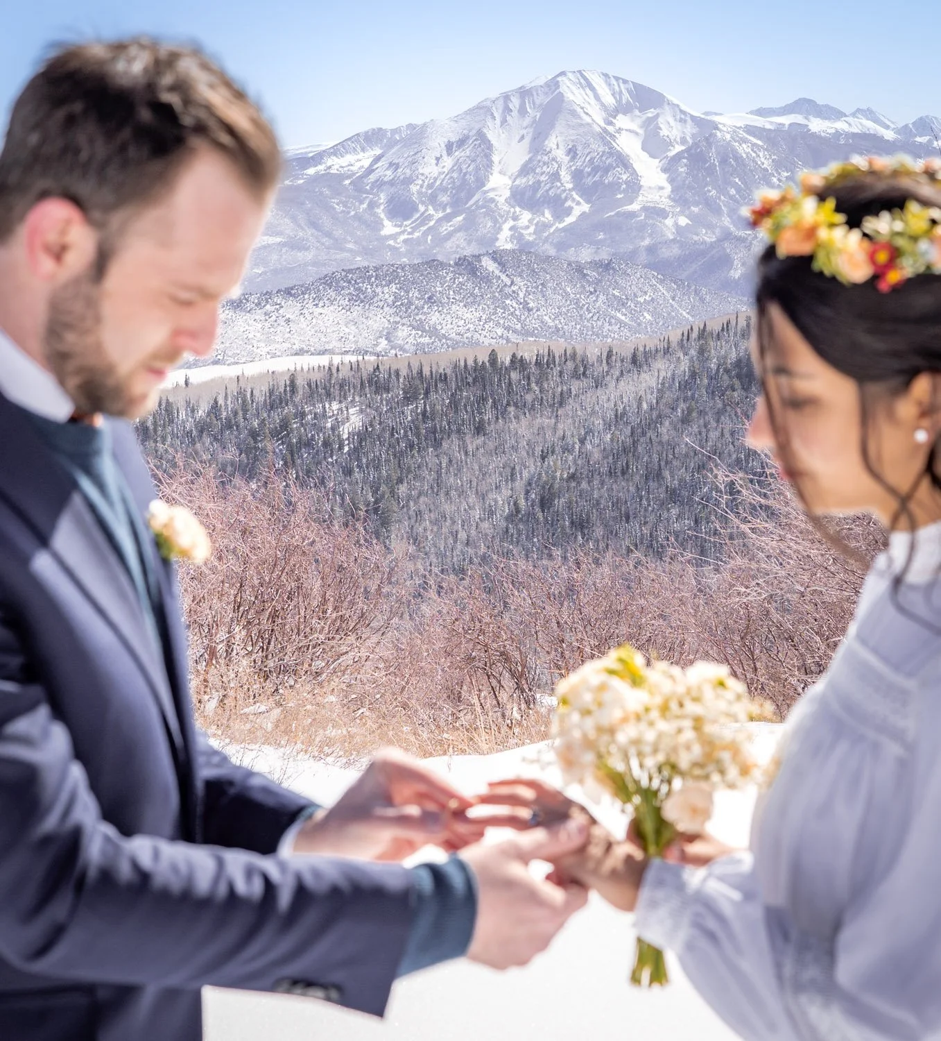 A bride and groom exchange rings on top of a ski resort in Colorado.