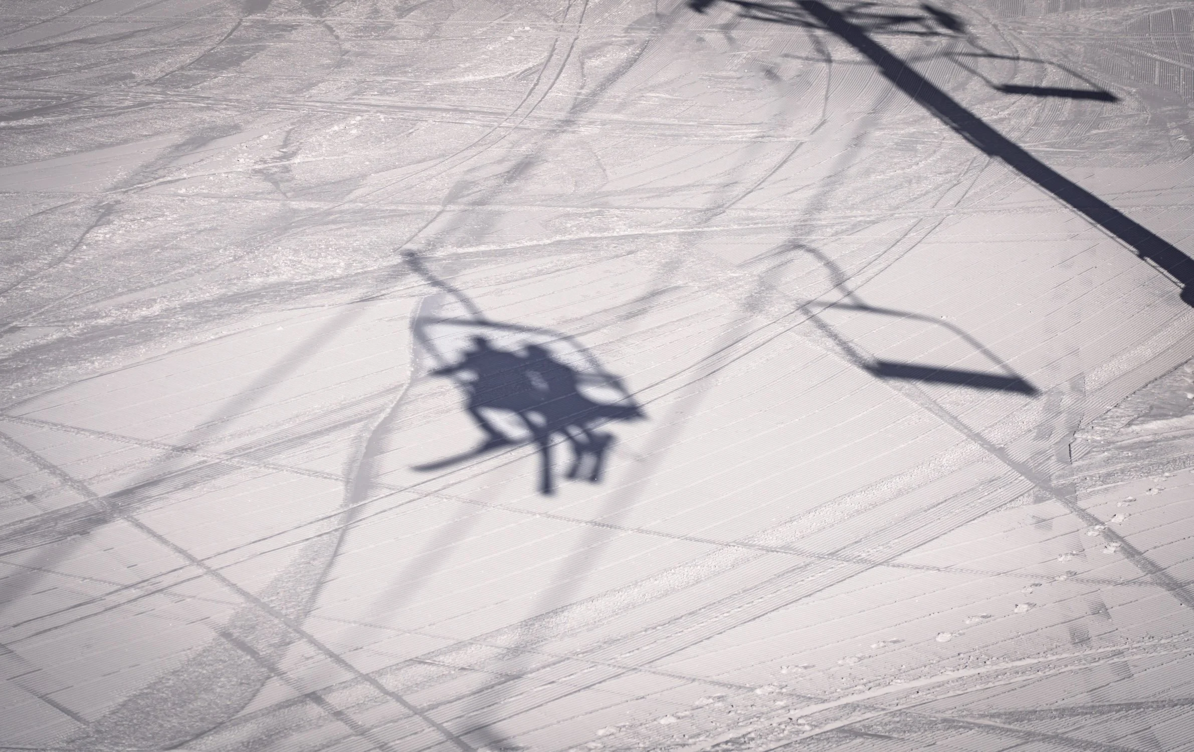 A shadow of a bride and groom on a ski chairlift.