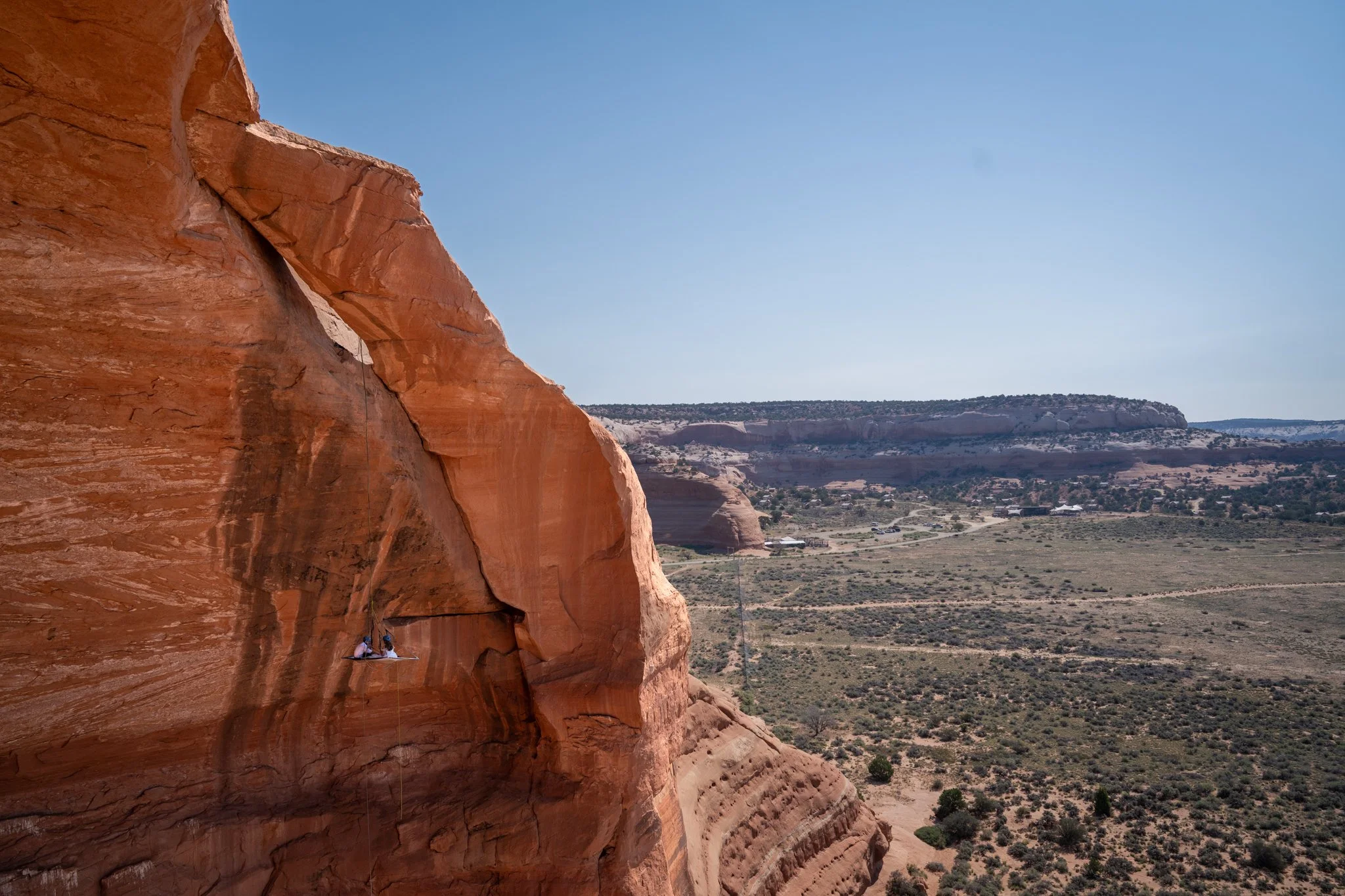 A bride and groom enjoy lunch and beer from a rock climbing suspended portaledge in Moab, Utah.