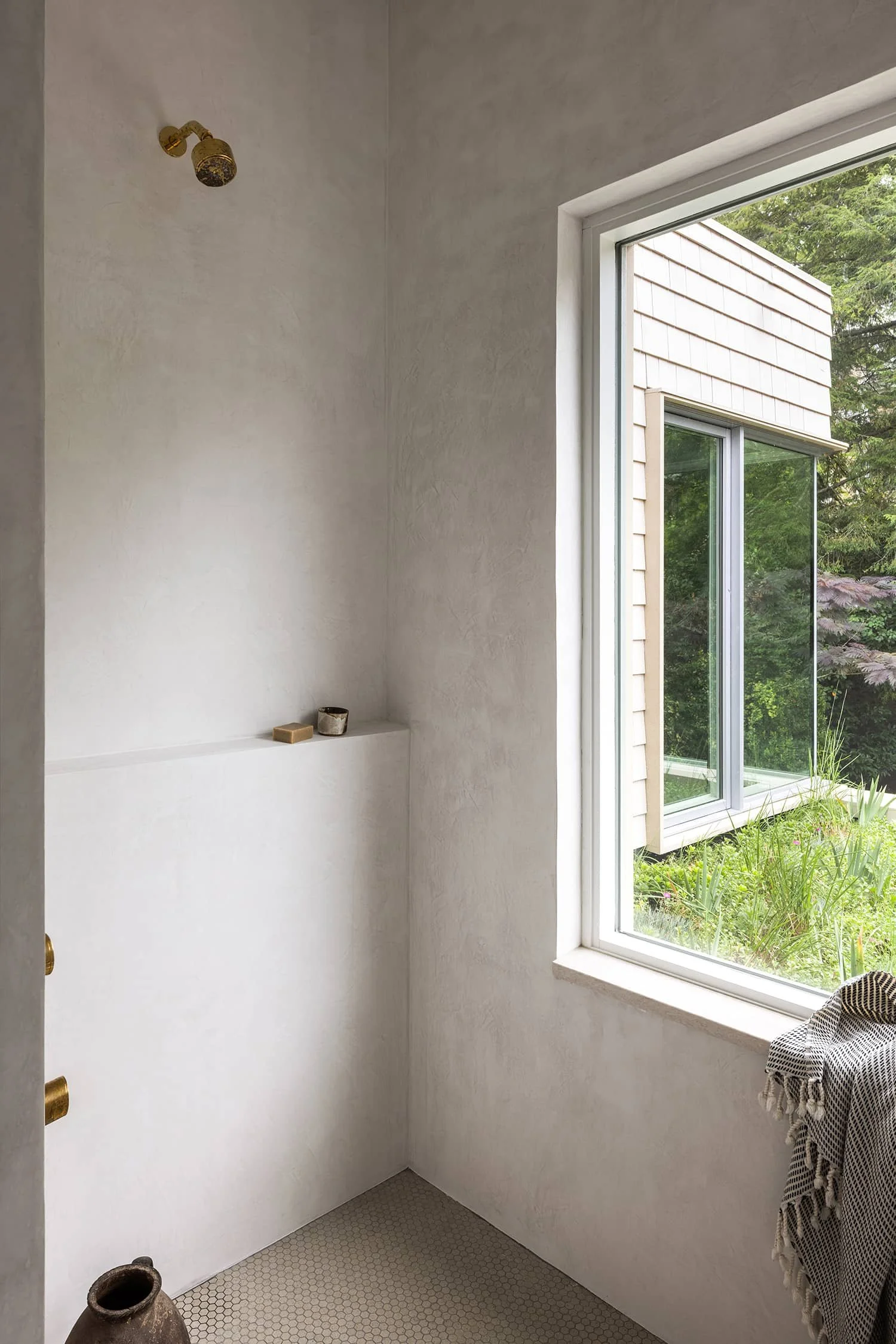 Shower in light venetian plaster with large window overlooking garden designed by Fowlkes Studio in Kalorama Washington, DC.