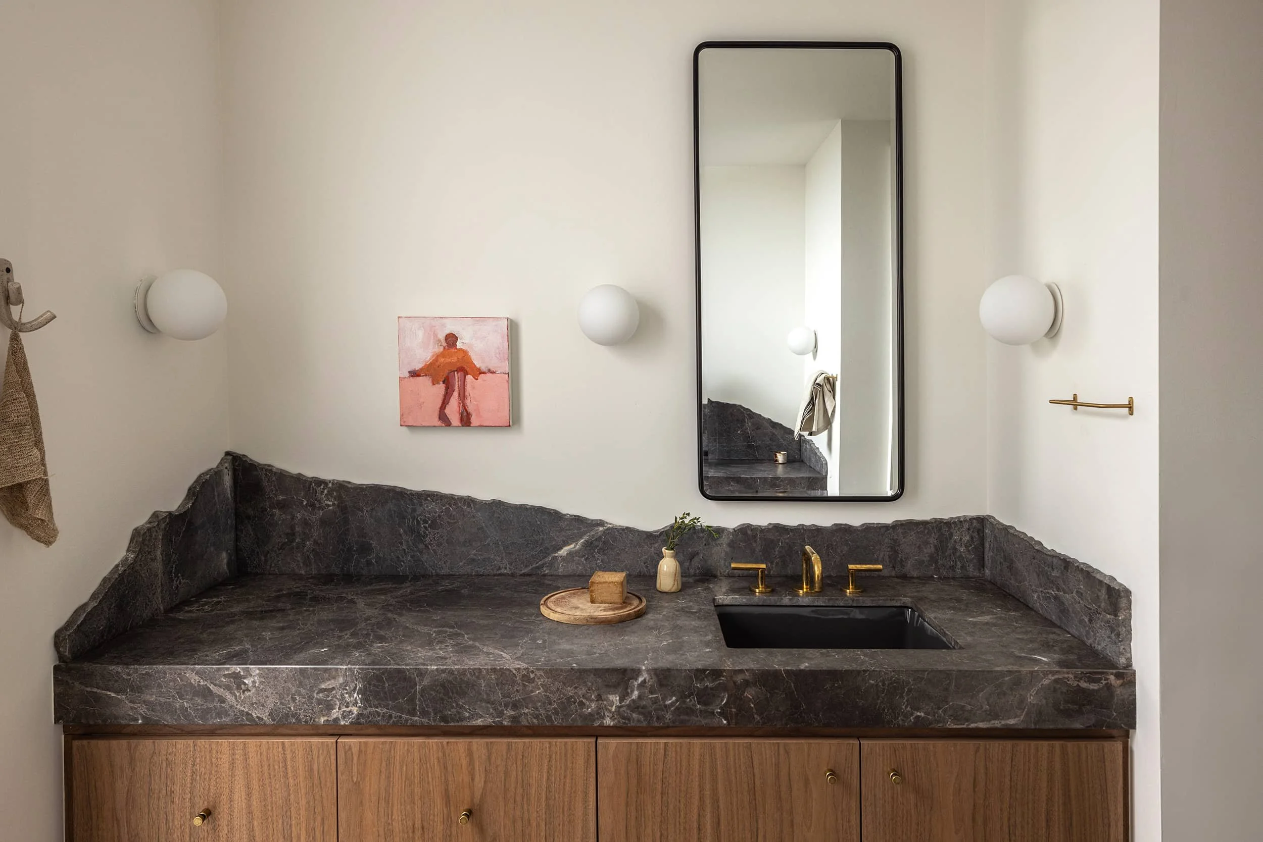 Bathroom with sculptural stone sink with rough, free edge backsplash designed by Fowlkes Studio in Washington, DC