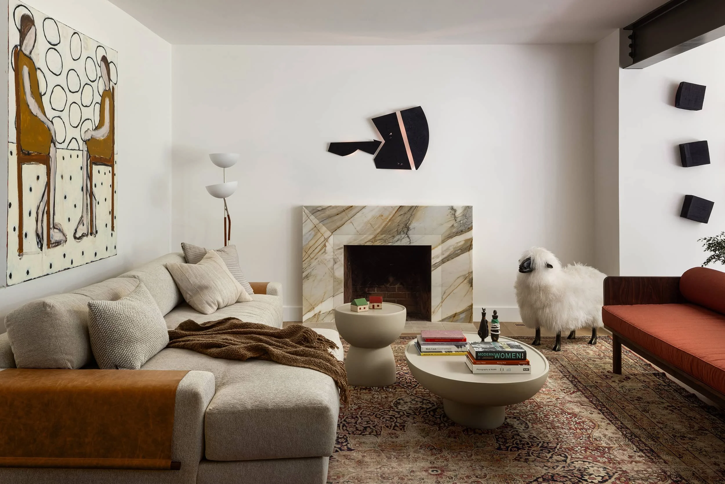 Modern living room with tan, beige, ochre, and red palette, marble fireplace surround, and sculptural sheep decor, designed by Fowlkes Studio in Washington, DC.