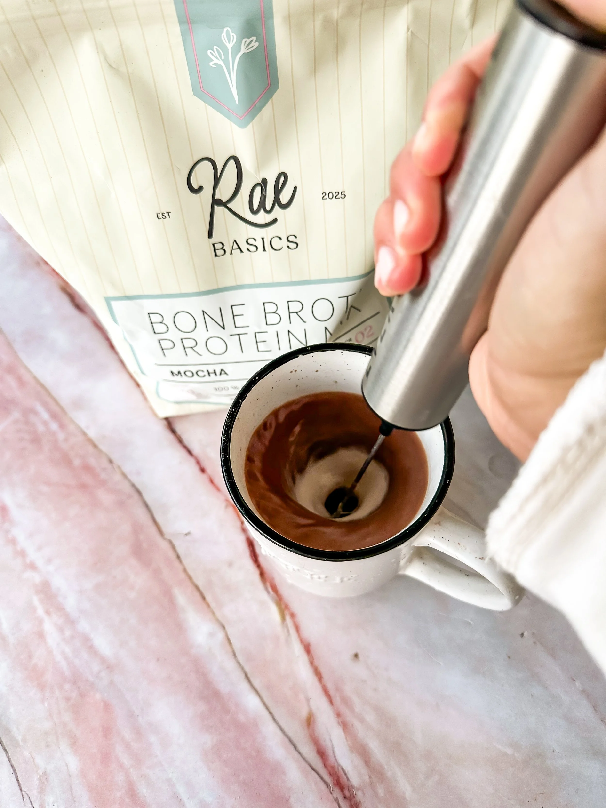 Using a handheld frother to blend RAE Basics Mocha Bone Broth Protein 