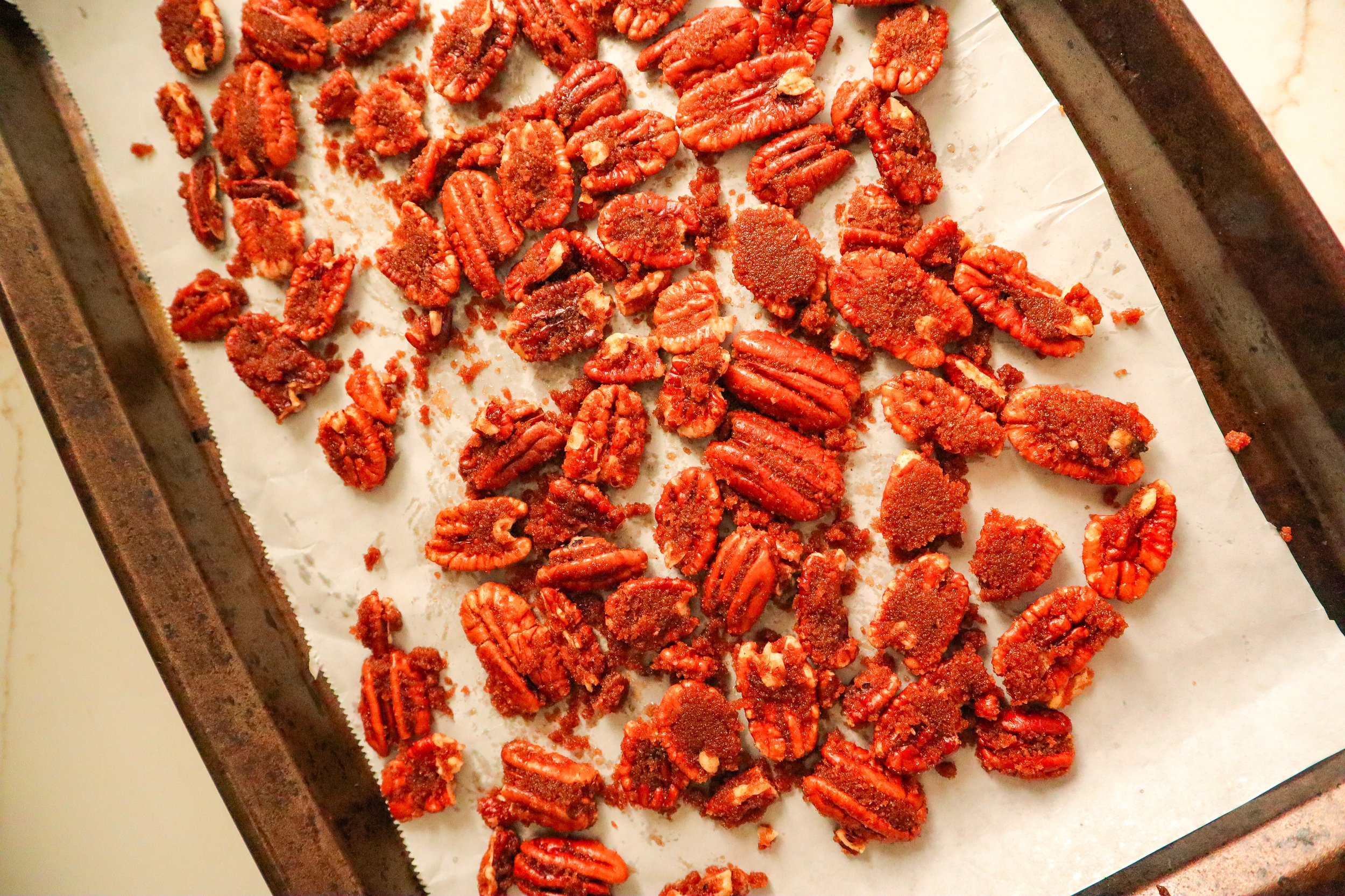  Freshly candied pecans cooling on parchment paper after cooking. 