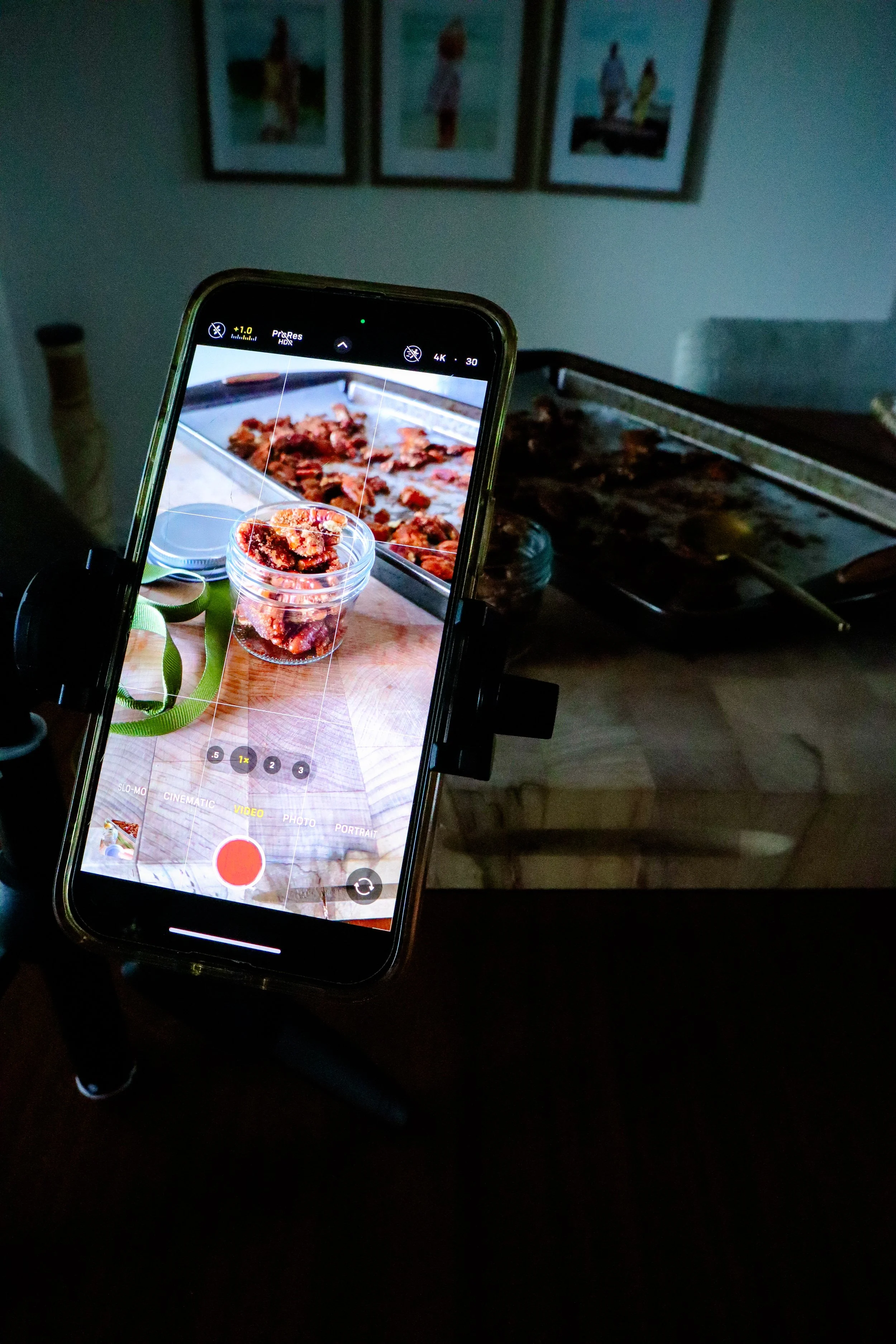  hone capturing a close-up photo of the finished praline pecans on a baking tray. 