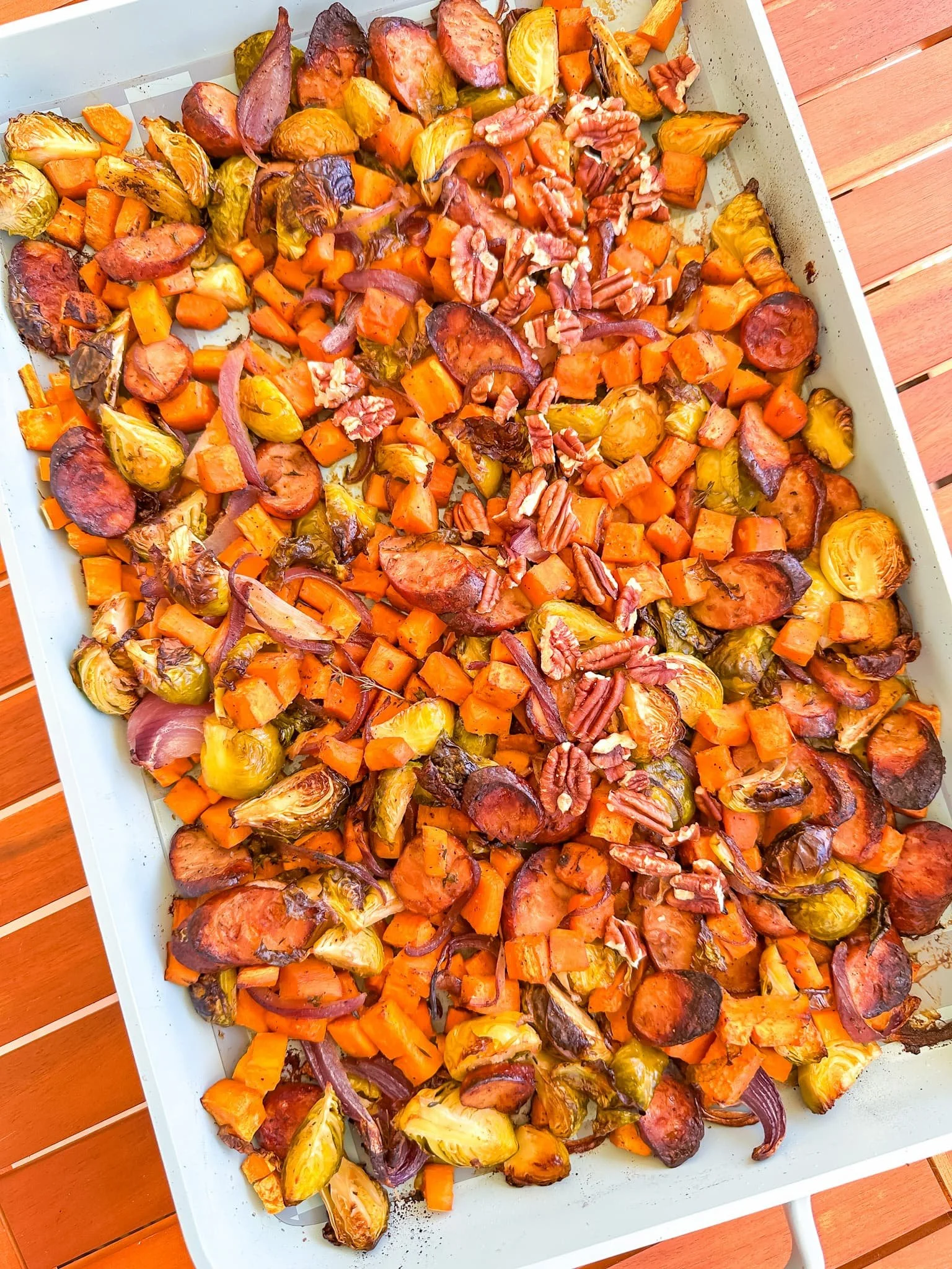   Roasted sweet potatoes, Brussels sprouts, and red onions on a sheet pan, golden and caramelized.  