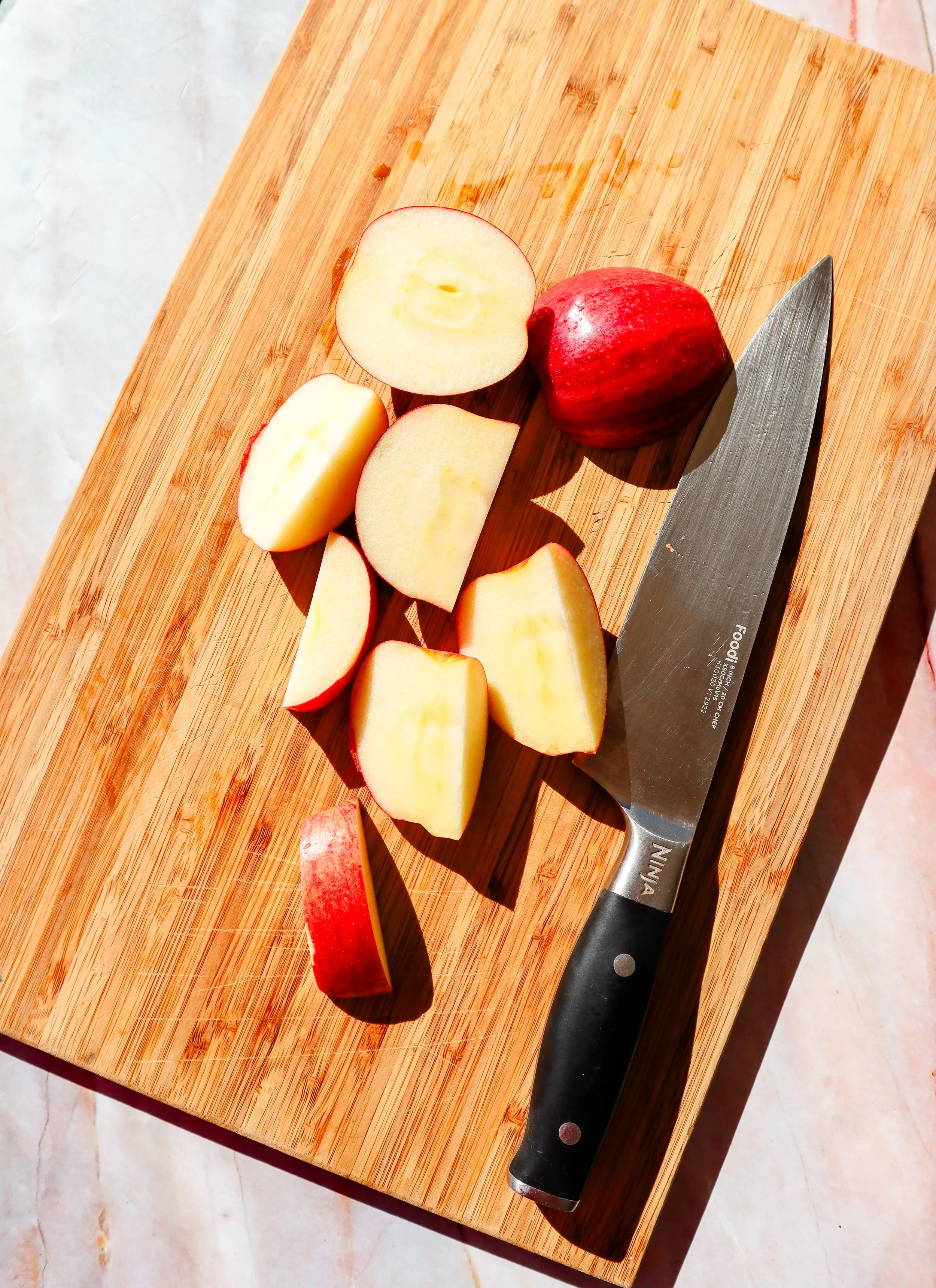  Sliced apples on a cutting board with a knife, prepared for air fryer apples. 