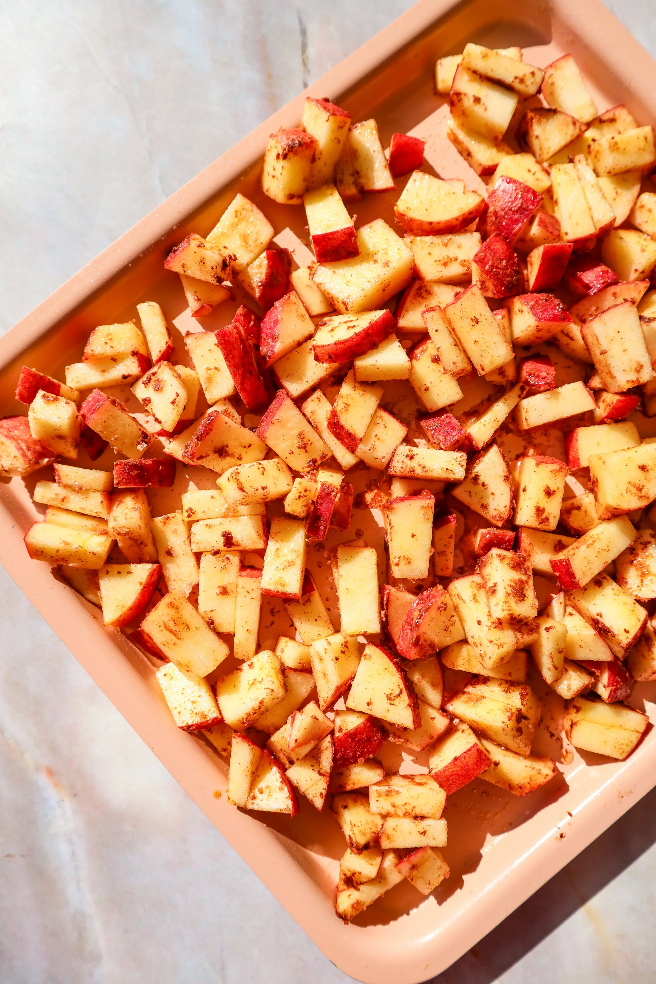  Seasoned apples arranged in an air fryer basket, ready to cook. 