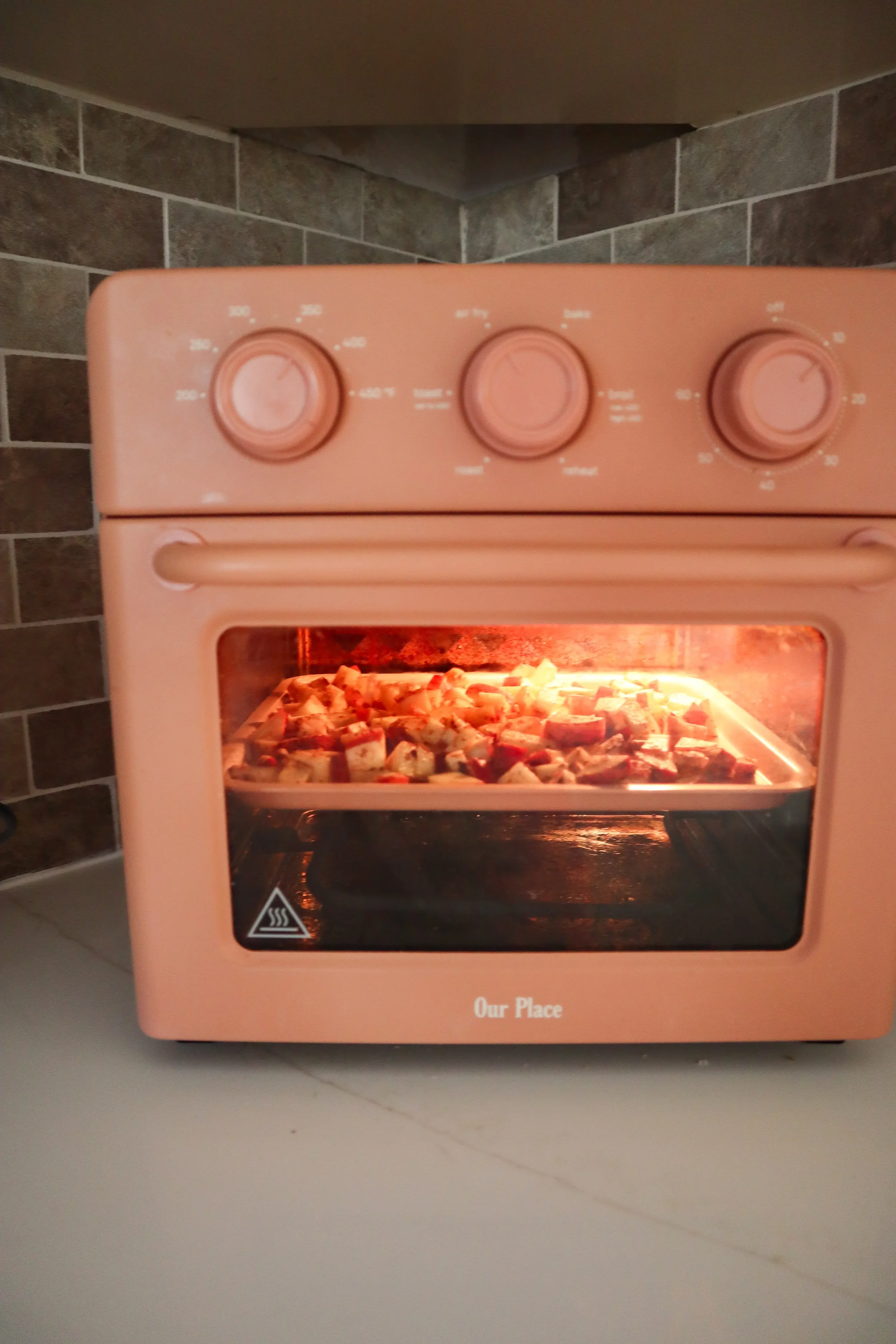  Air fryer apples cooking on a tray inside an air fryer oven. 