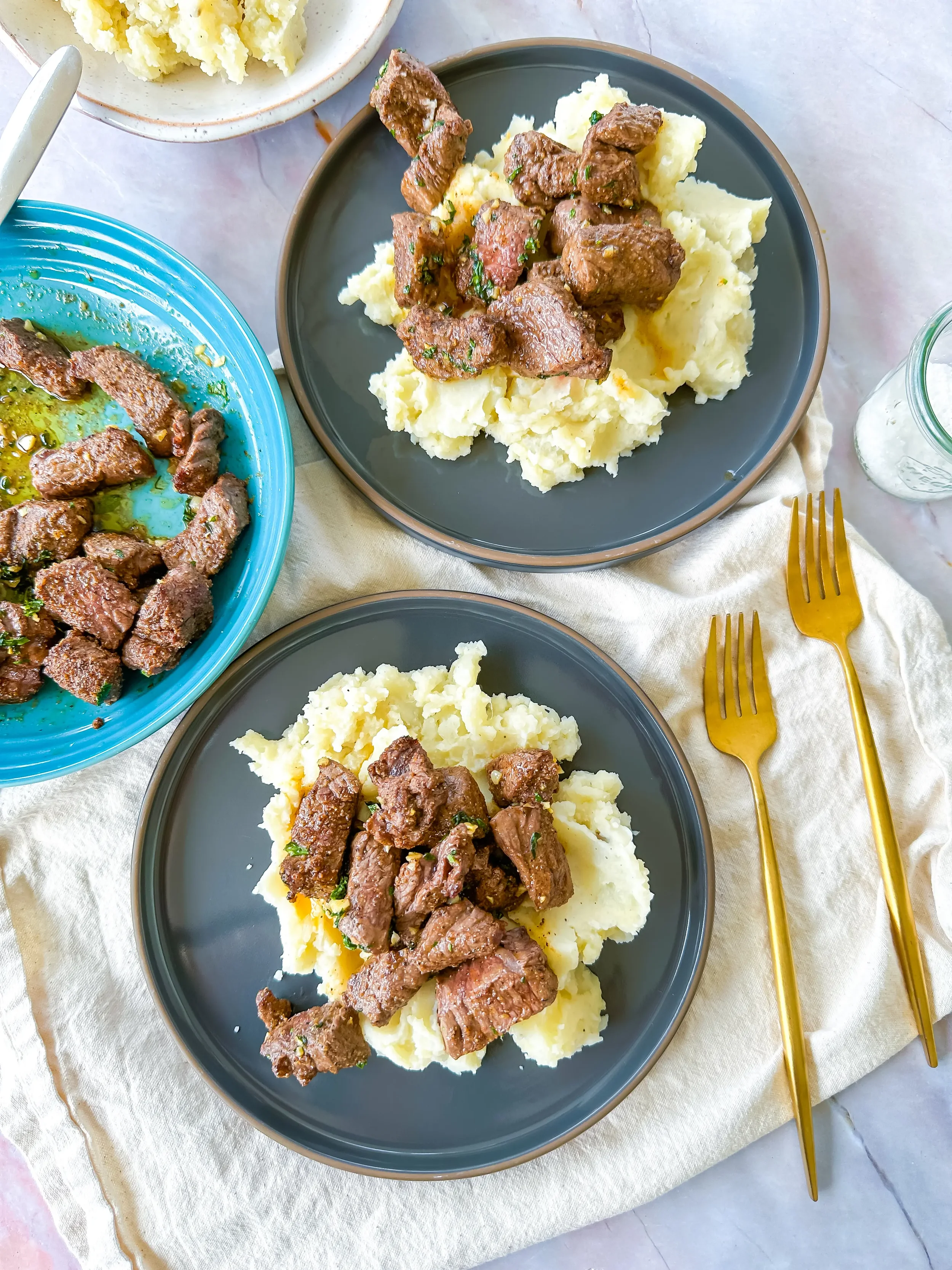 juicy steak bites with butter and garlic sauce on a pile of mashed potatoes