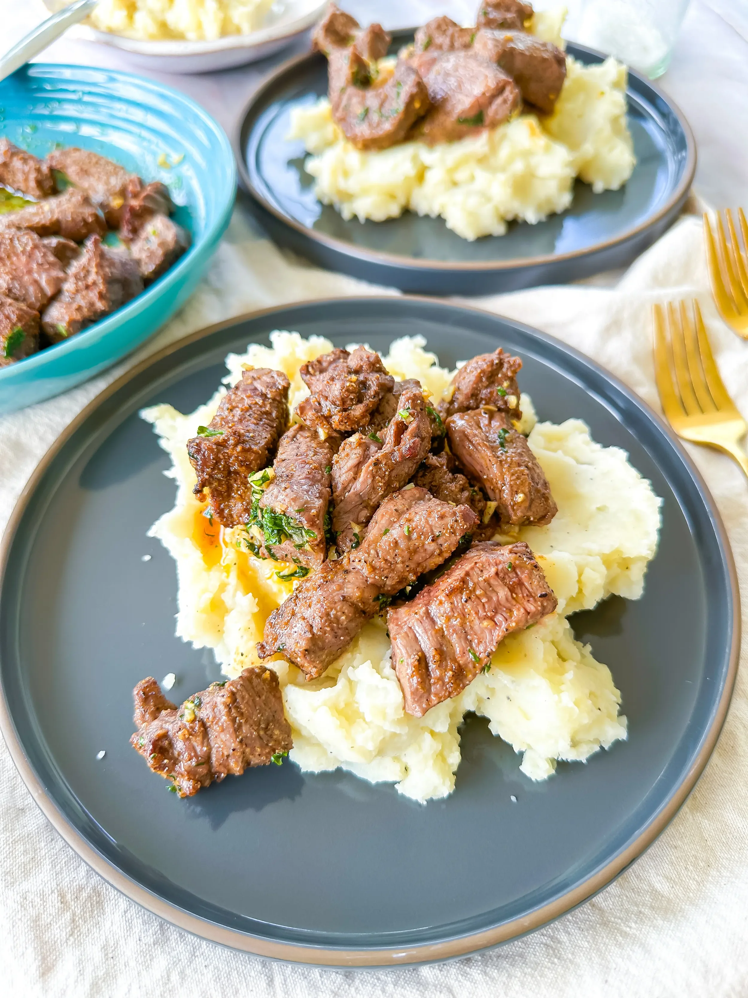 steak bites with garlic butter sauce plated on top of mashed potatoes
