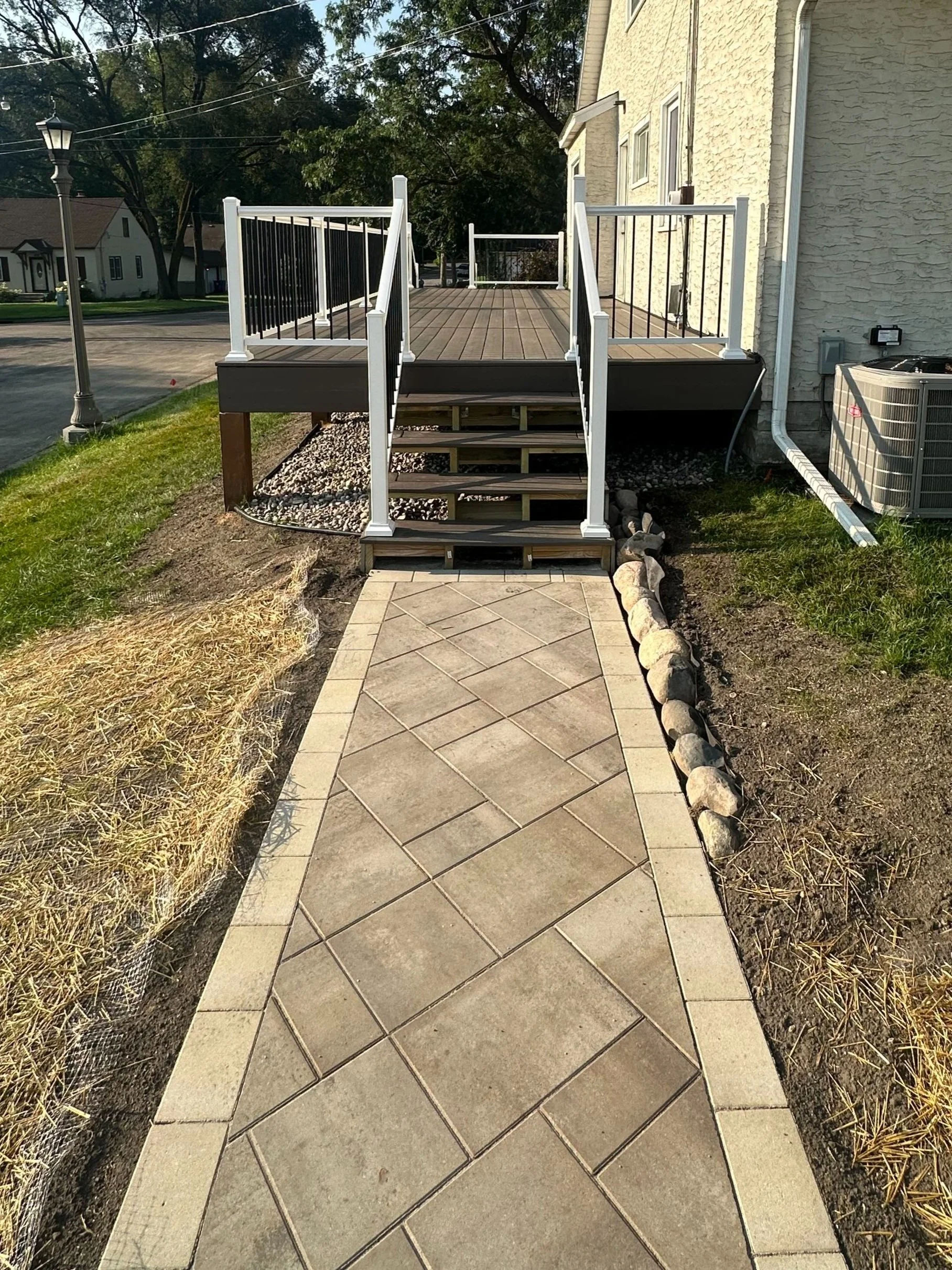 MB Landscapes installed a curved paver walkway and stamped concrete steps leading from sidewalk to house porch.