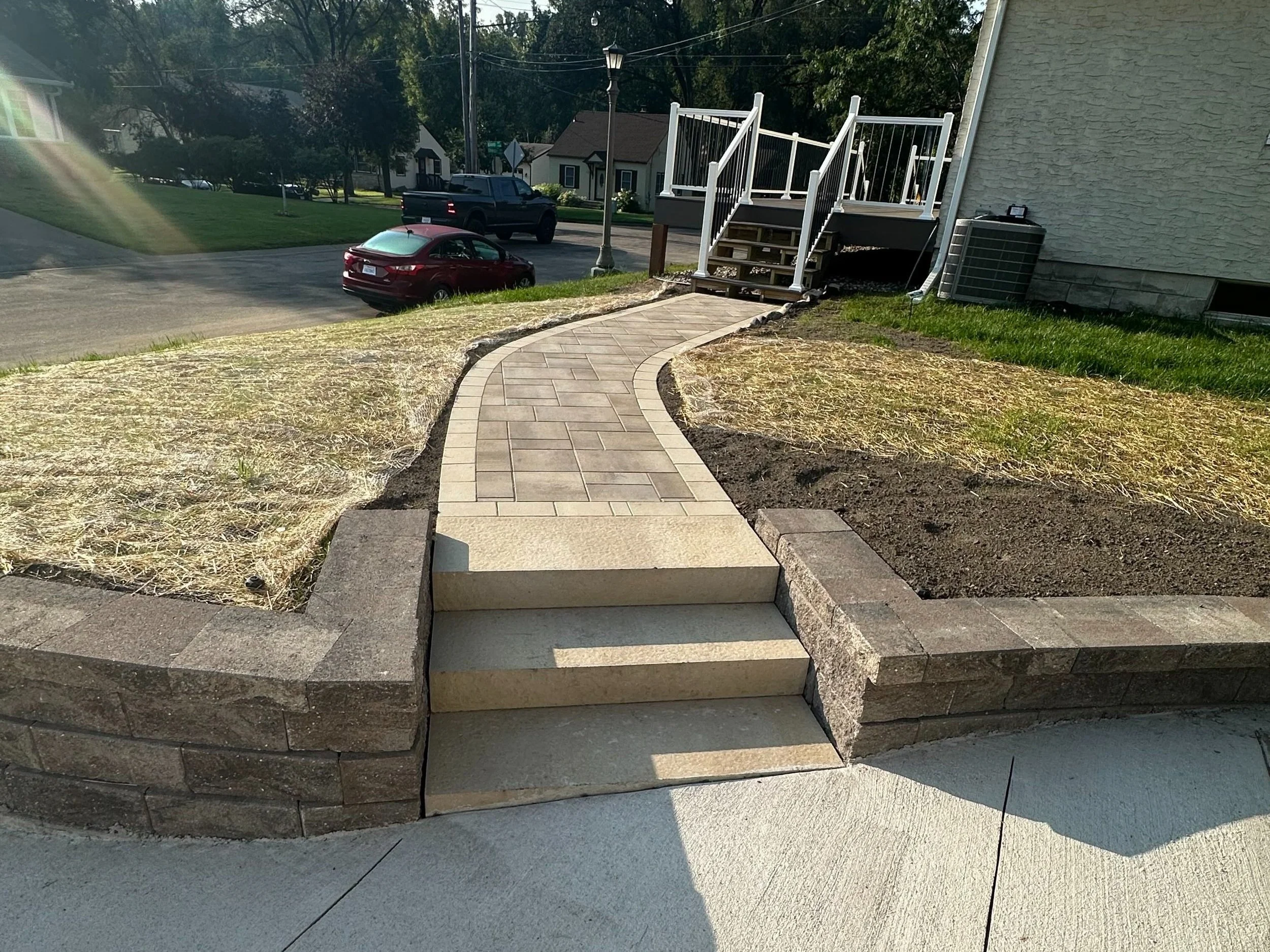 MB Landscapes installed a curved paver walkway and stamped concrete steps leading from sidewalk to house porch.