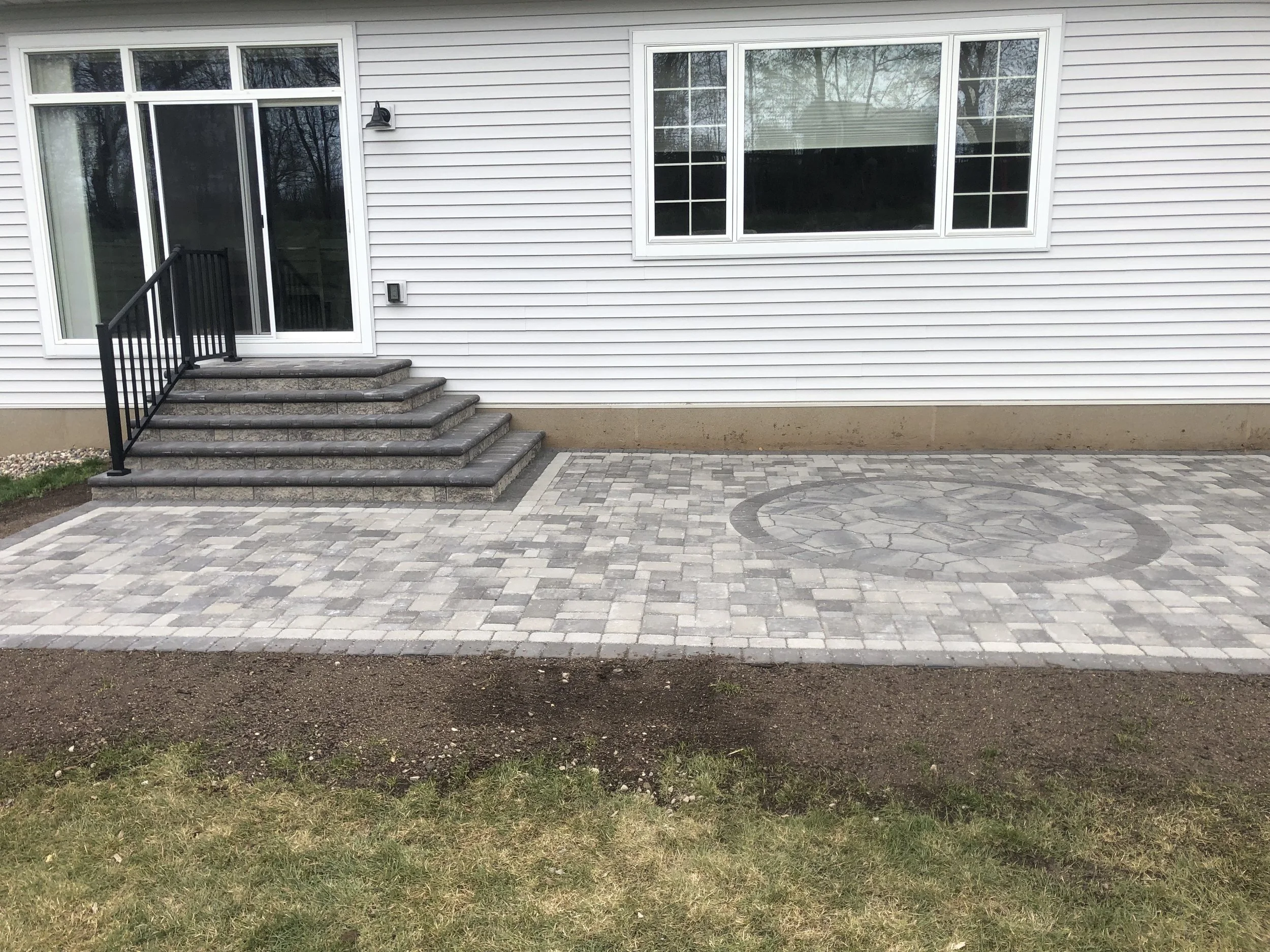 MB Landscapes installed a paver patio with a decorative inlay. Also installed a double sided paver stairway to the sliding door.