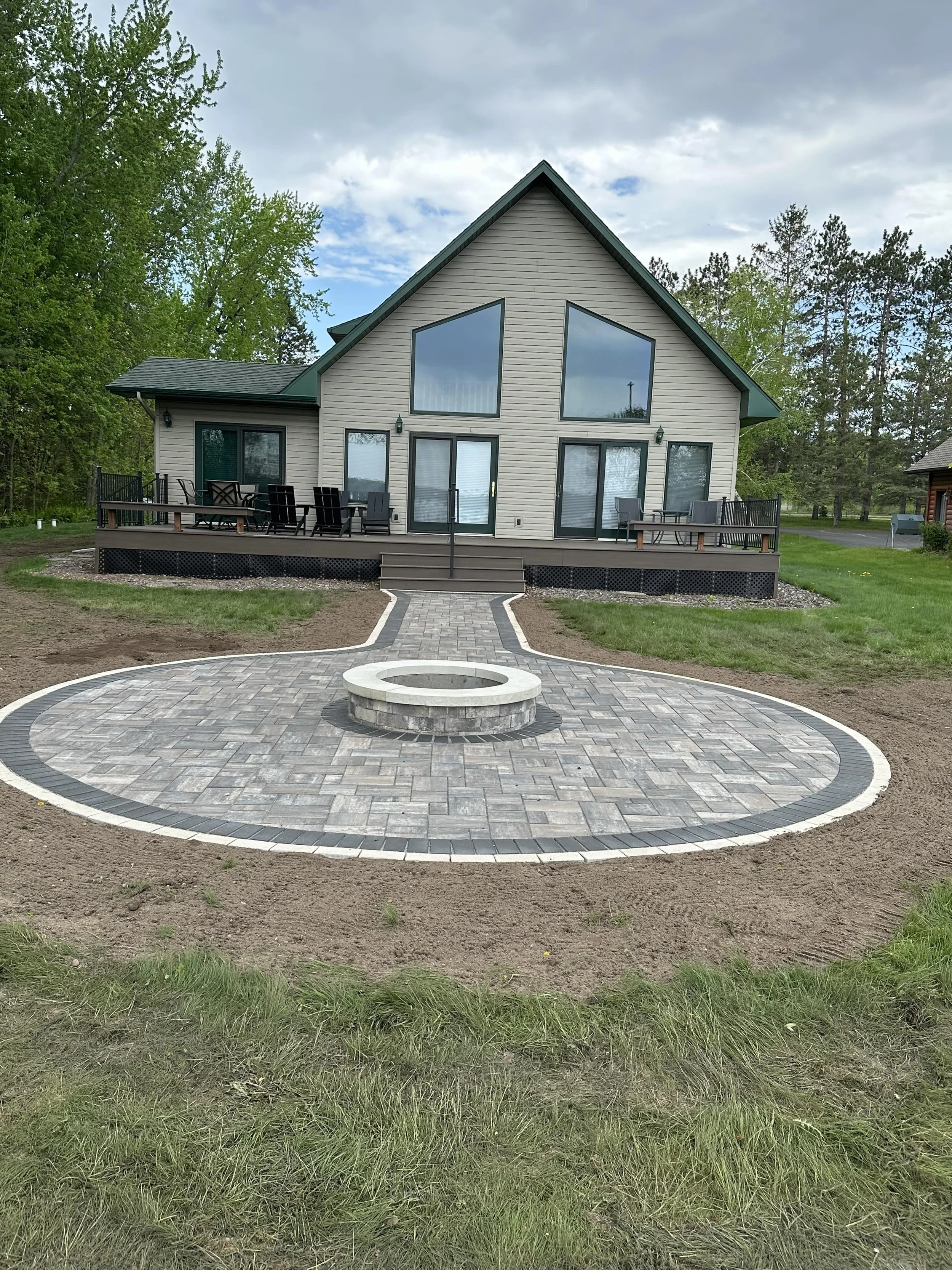 MB Landscapes newly paved walkway leading to a fire pit by a lake.