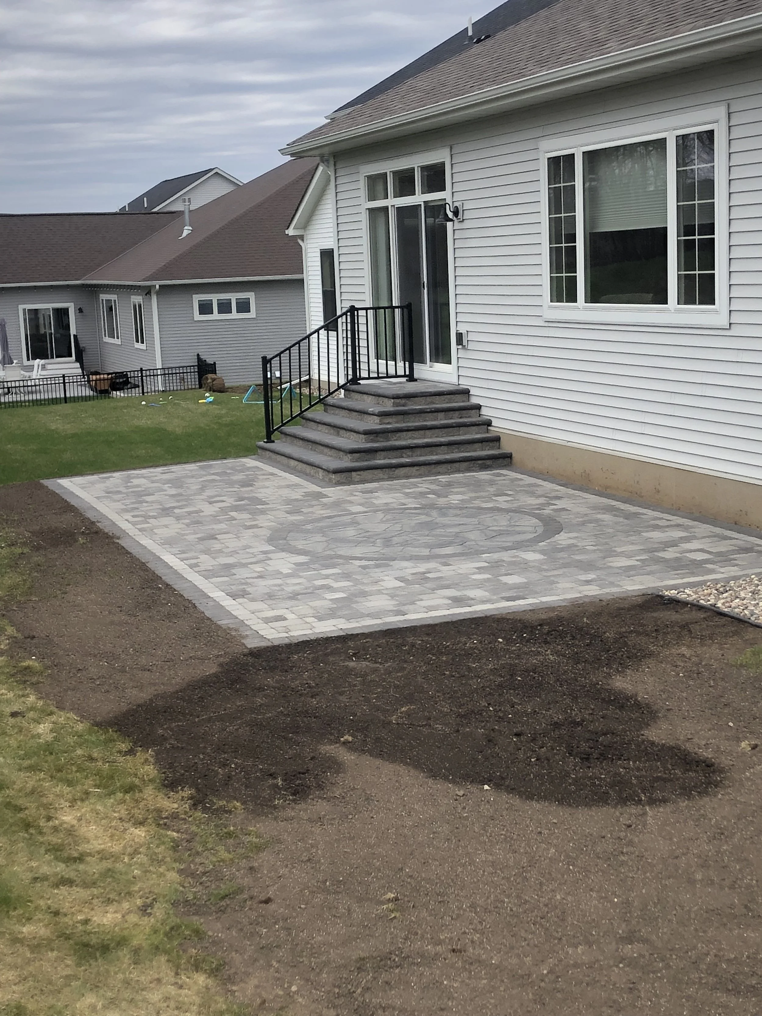 MB Landscapes installed a paver patio with a decorative inlay. Also installed a double sided paver stairway to the sliding door.